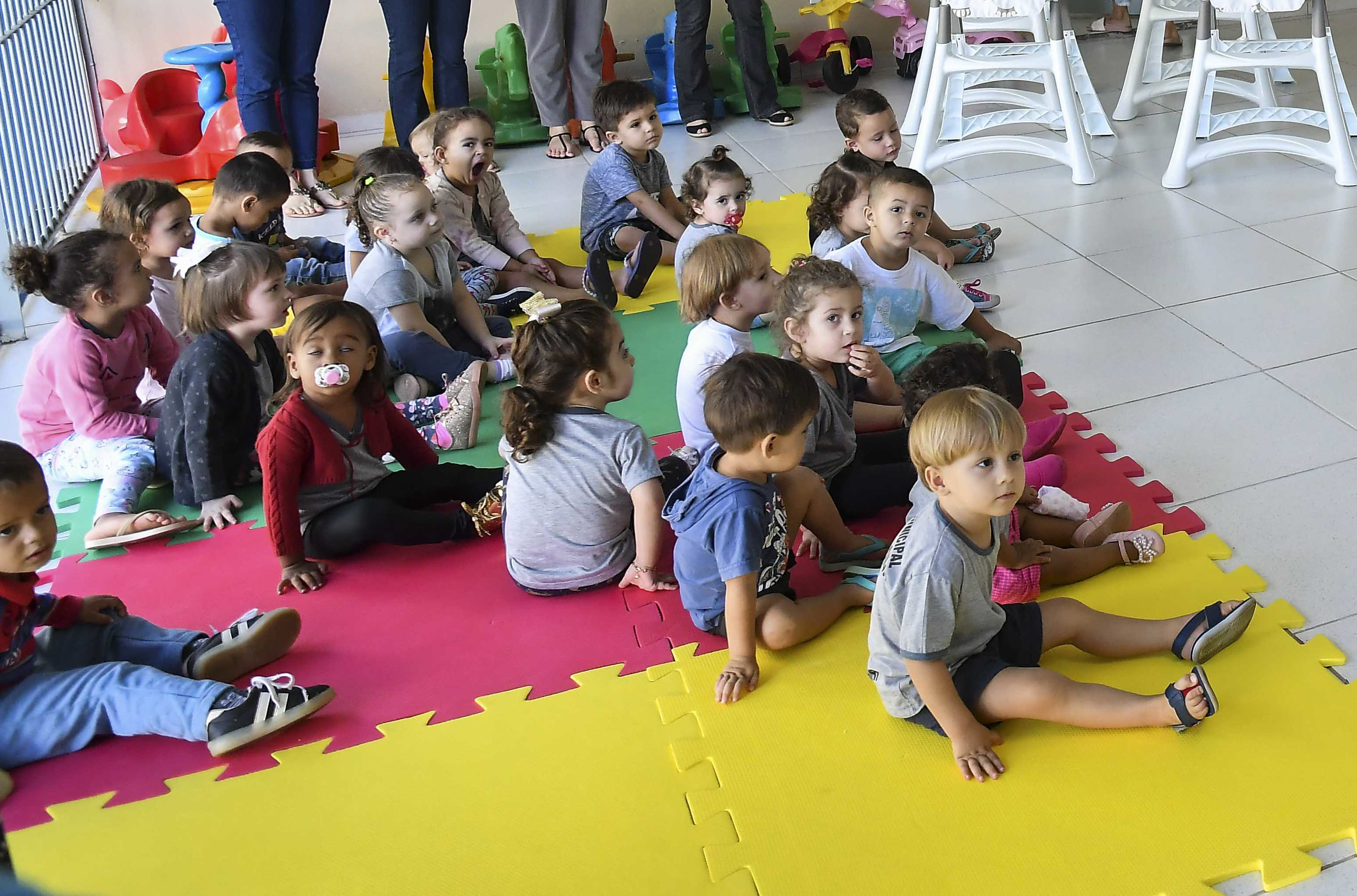 Crianças pequenas sentadas sobre um tatame em creche do município de Umuarama