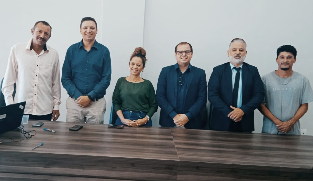 Cinco homens e uma mulher em pé, atrás de uma mesa de madeira