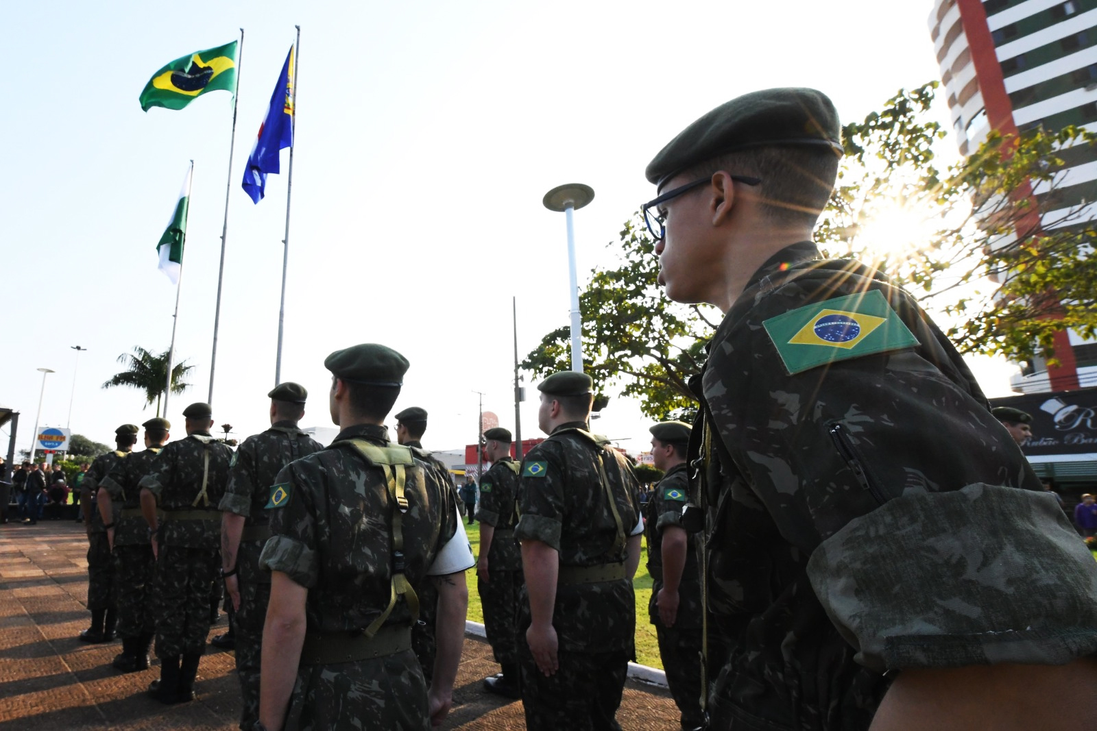 Jovens fardados observam o hasteamento das bandeiras em praça pública de Umuarama
