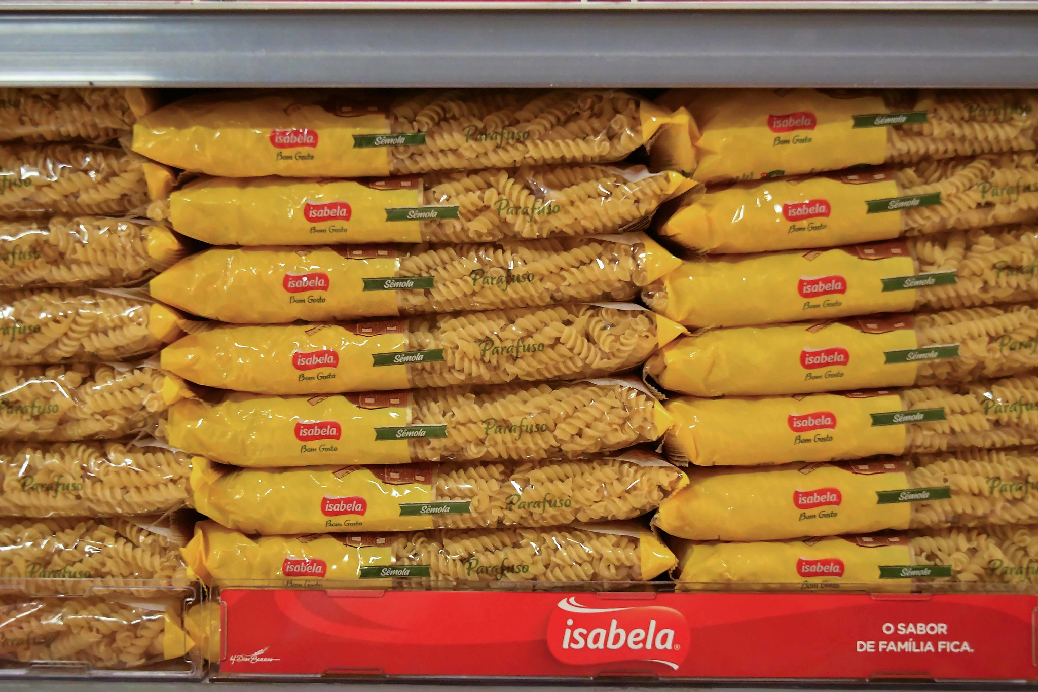 vários pacotes de macarrão parafuso em uma prateleira de supermercado