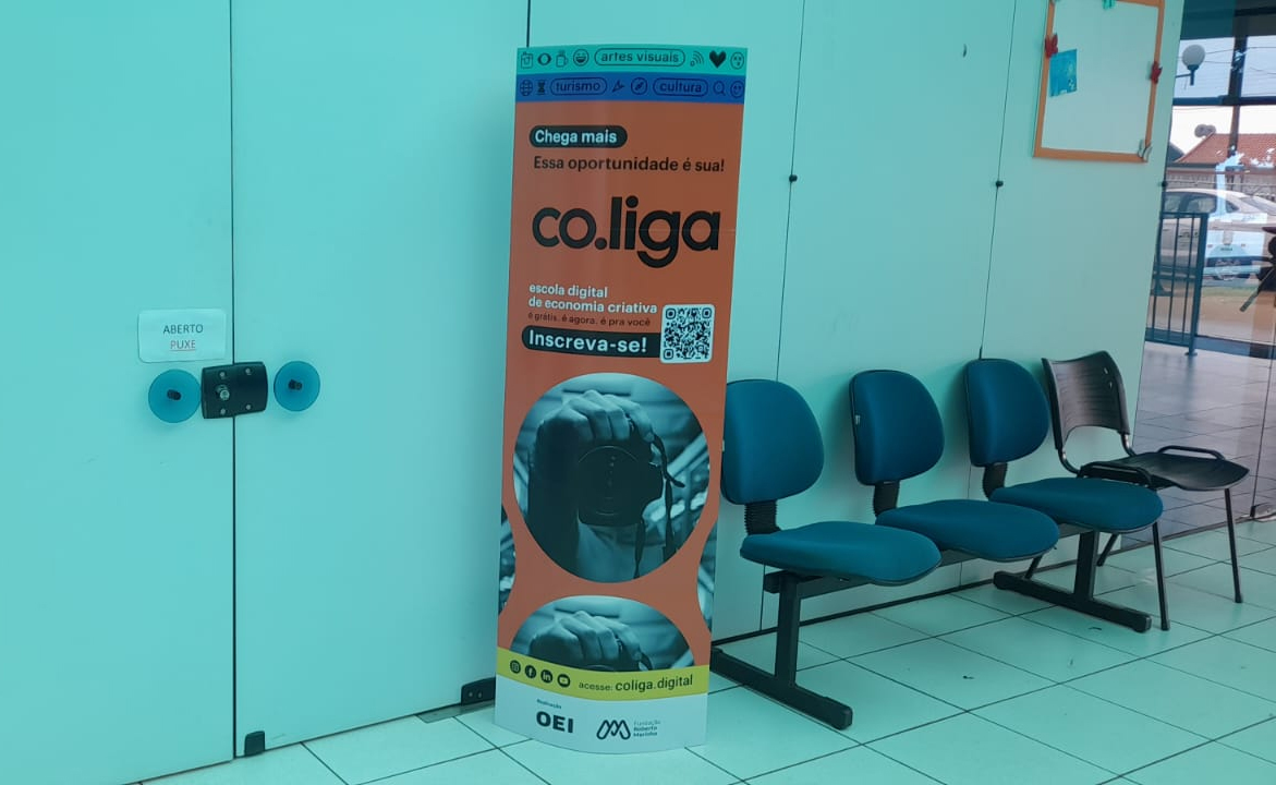 Cadeiras ao lado de um painel com a divulgação da escola digital
