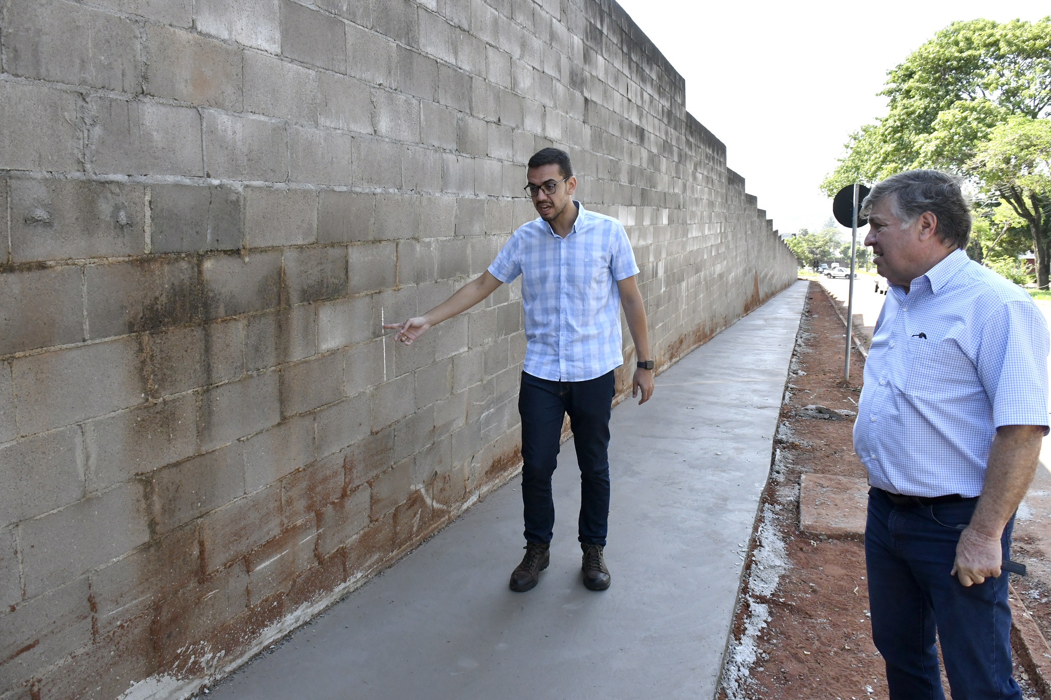 Prefeito e secretário observam construção de calçadas ao lado do muro do cemitério