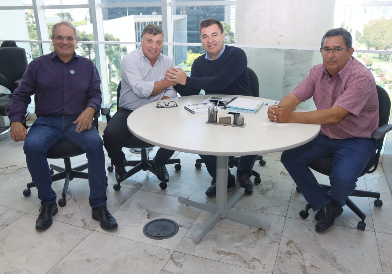 prefeito e dois secretários municipais em uma mesa, com o representante do governo do estado