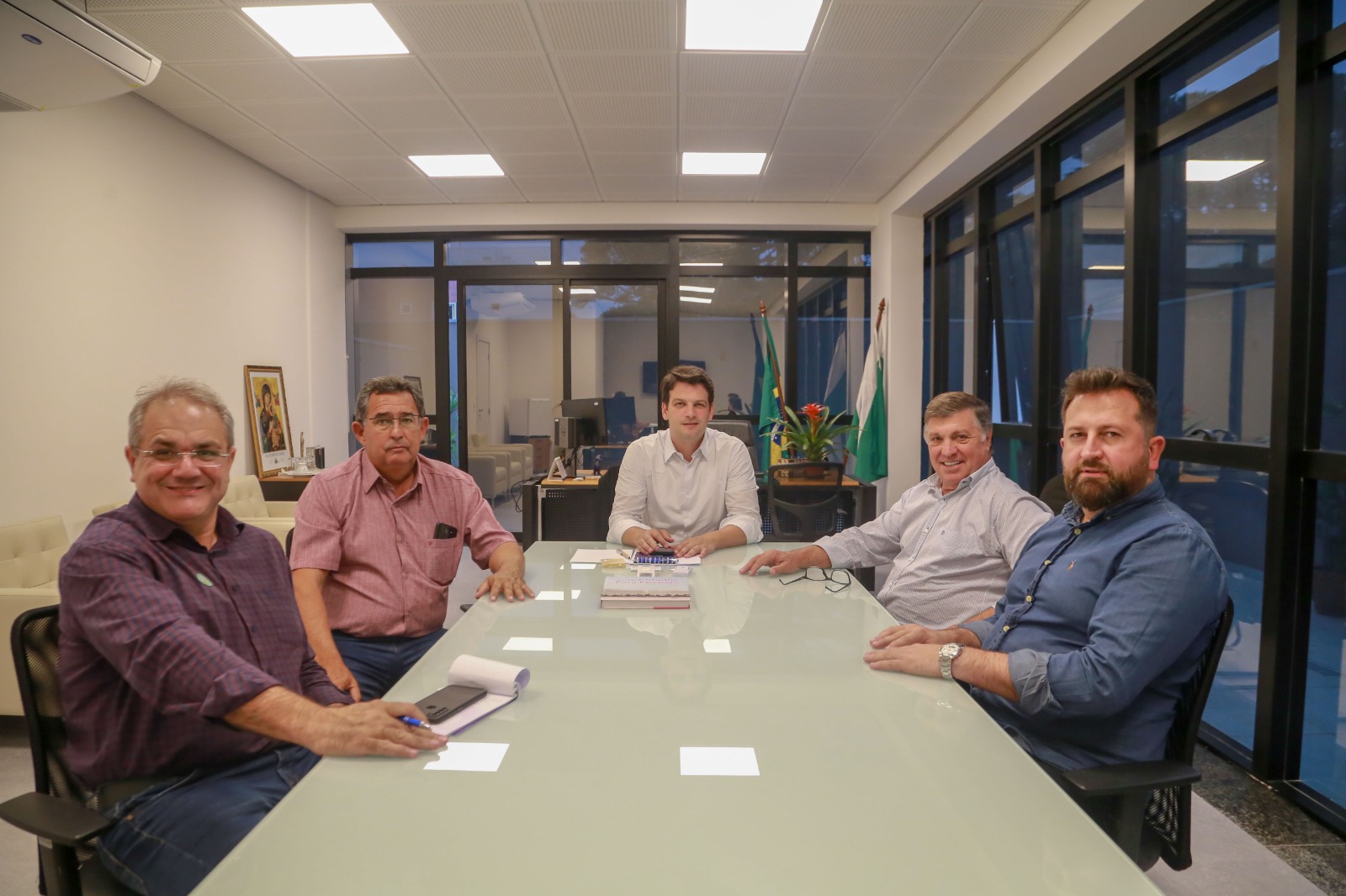 prefeito e lideranças politicas reunidos em torno de uma mesa posam para foto