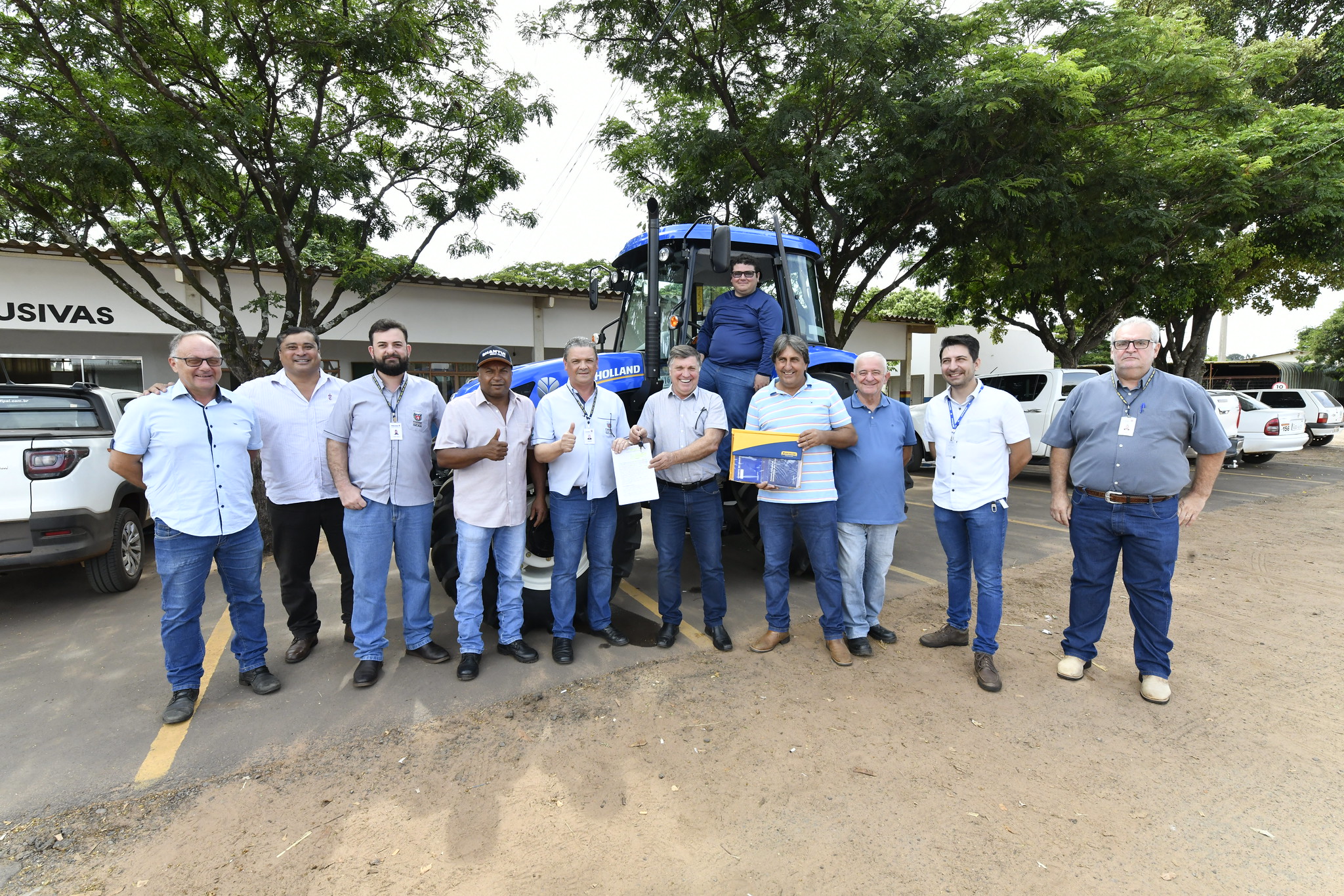 autoridades posam para foto ao lado do trator que foi entregue à secretaria de agricultura