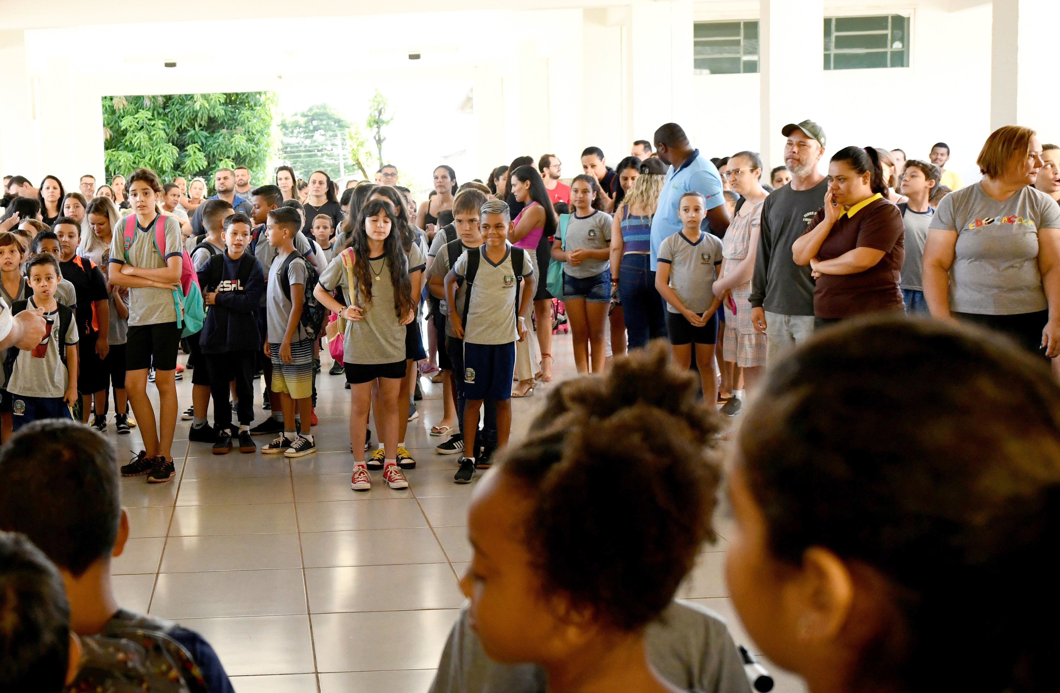 alunos e alunas perfilados em pátio de escola municipal