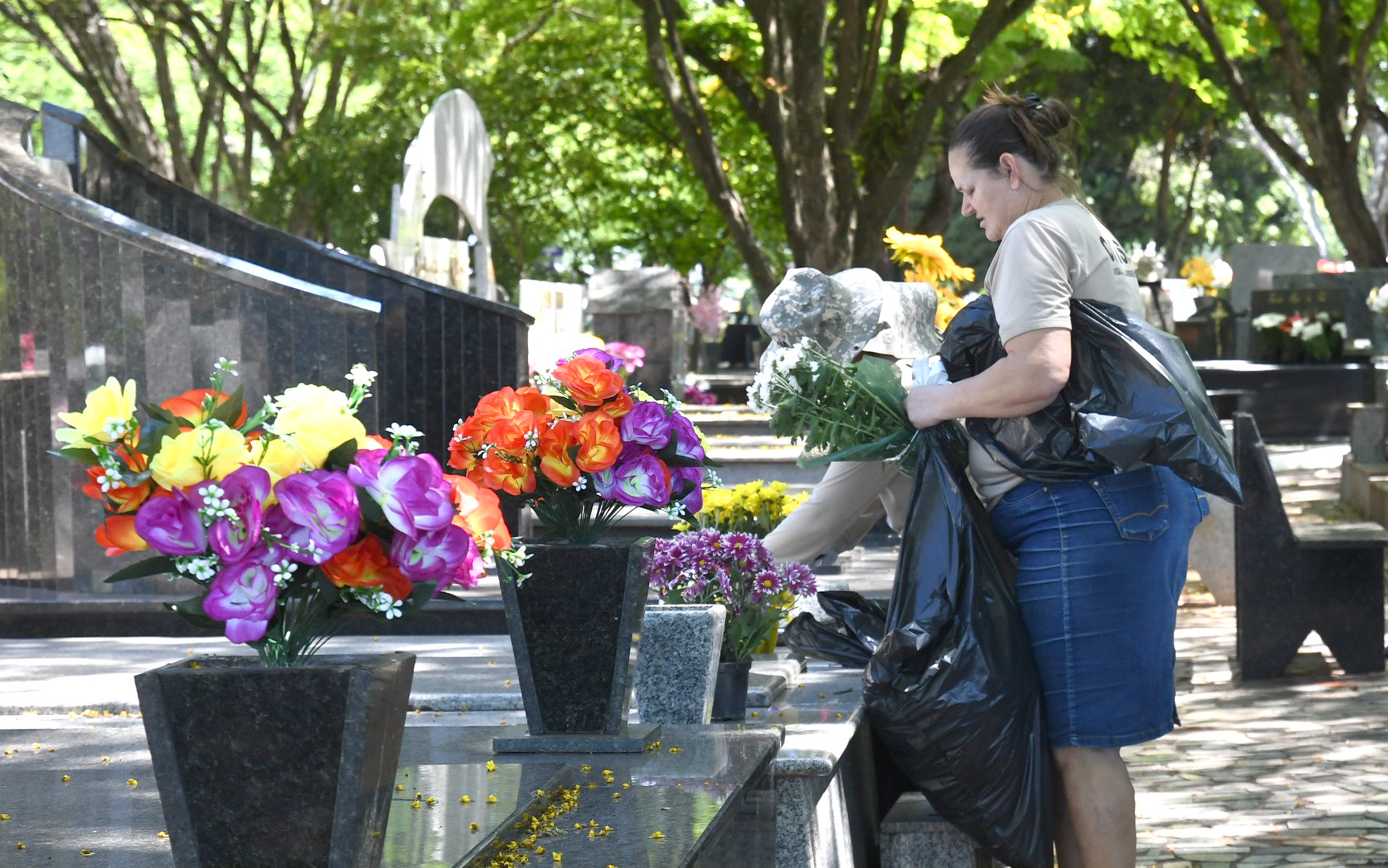 mulher em vista ao cemitério, colocando flores em um túmulo