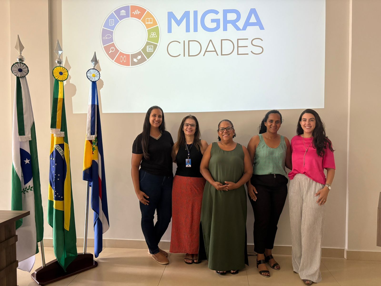 Equipe responsável pelo programa migracidades posa para foto; são cinco mulheres