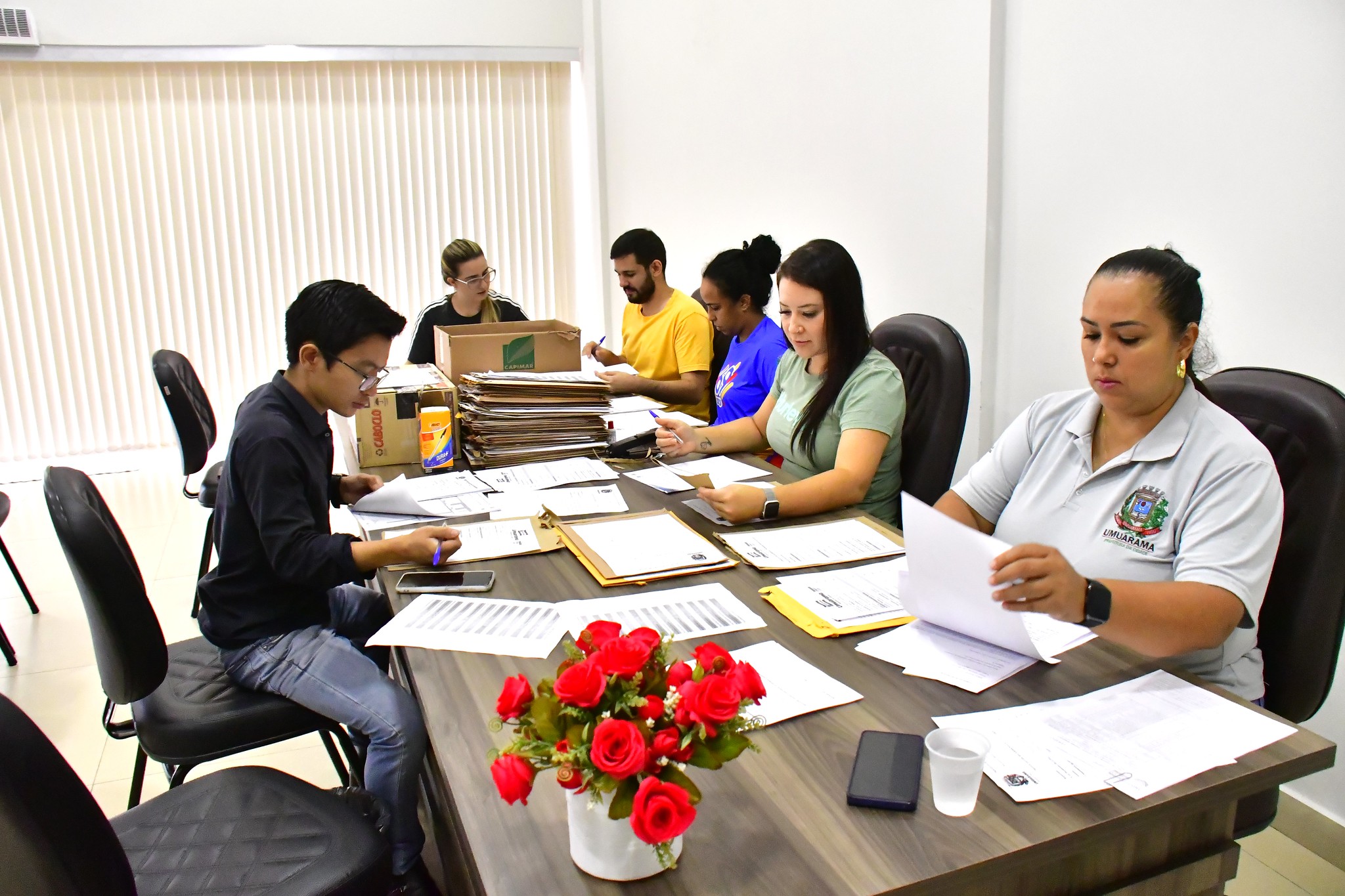 pessoas da comissão avaliam as inscrições reunida em volta de uma mesa