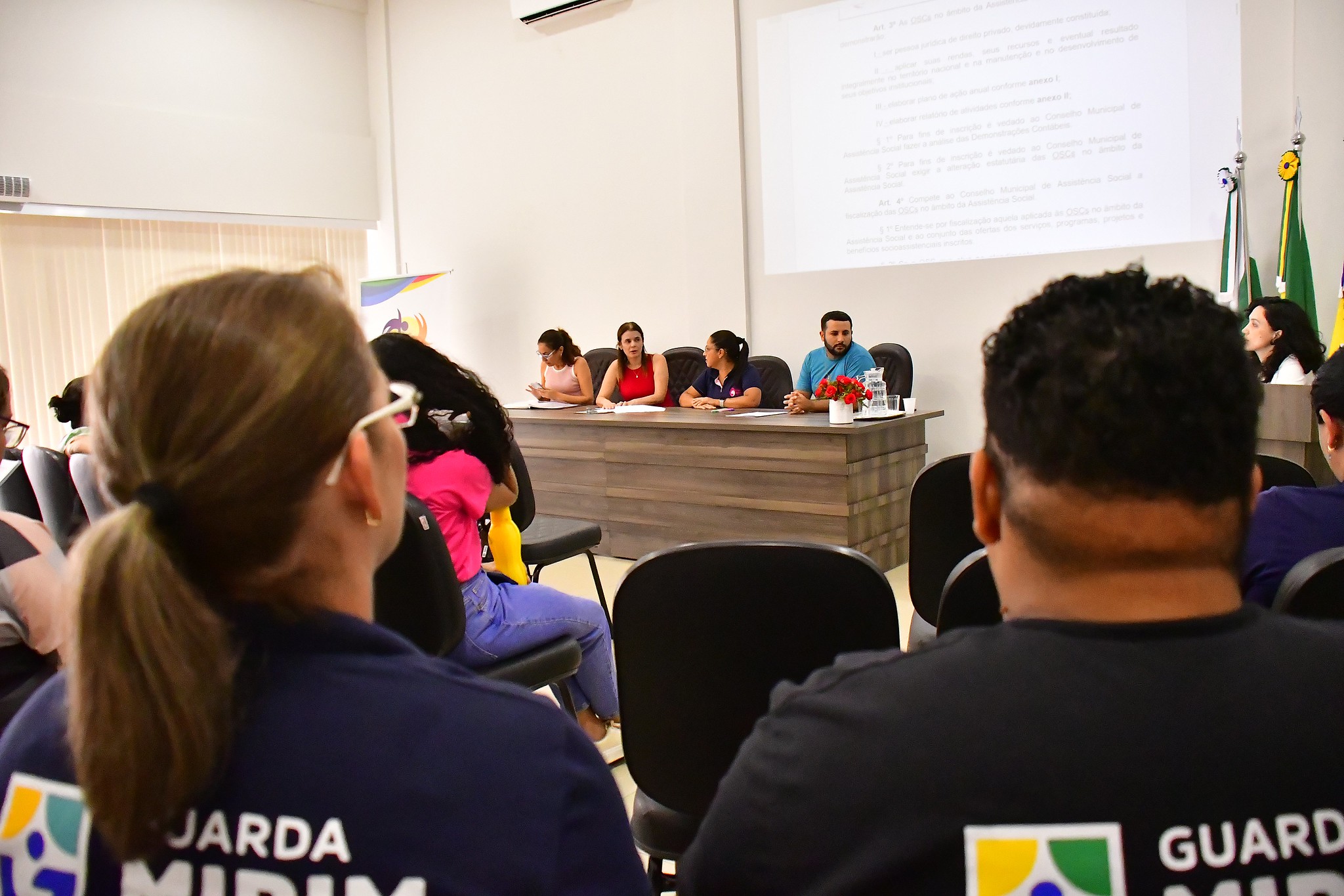 Momento da reunião, com pessoas observando a mesa das autoridades