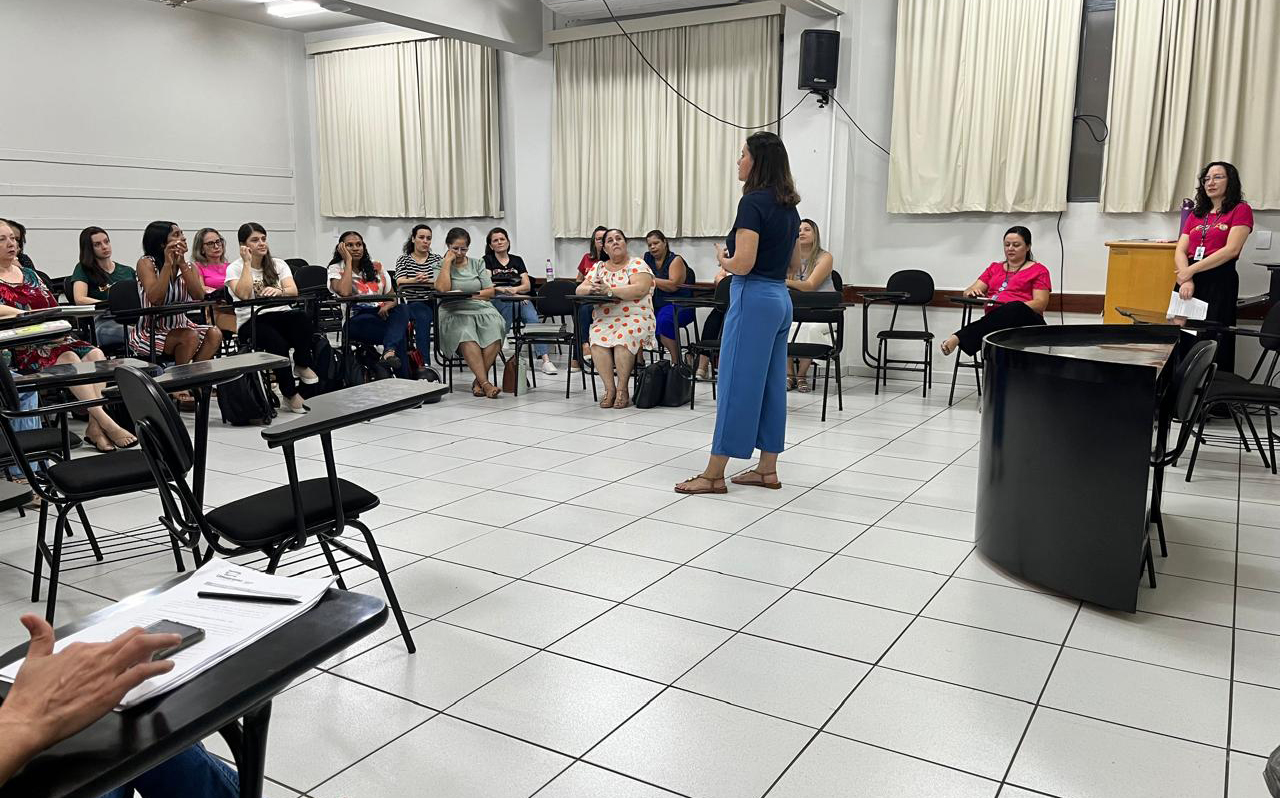 professora fala para outros professores no centro de uma sala de aula