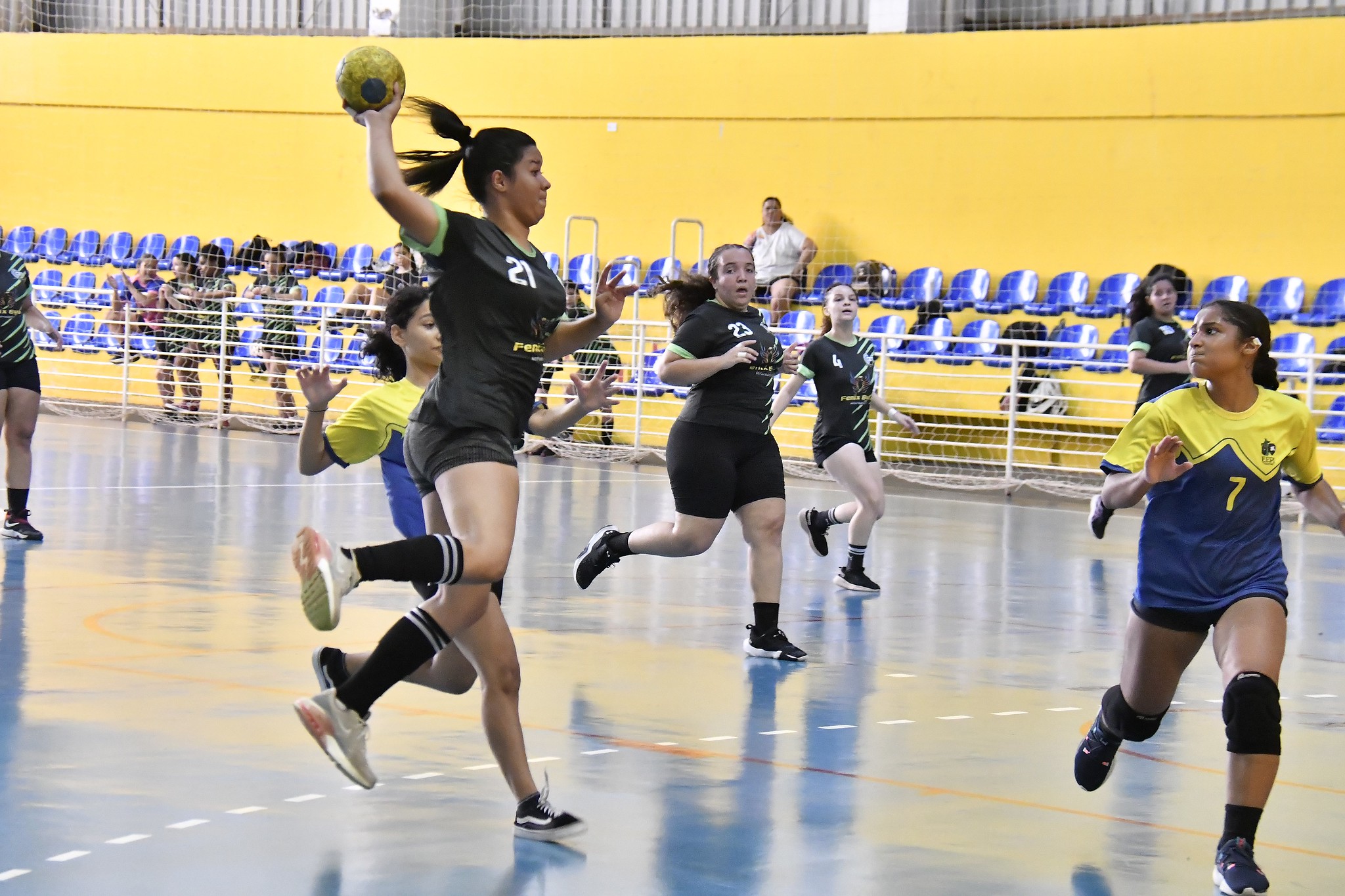 disputa de handebol feminino em quadra esportiva