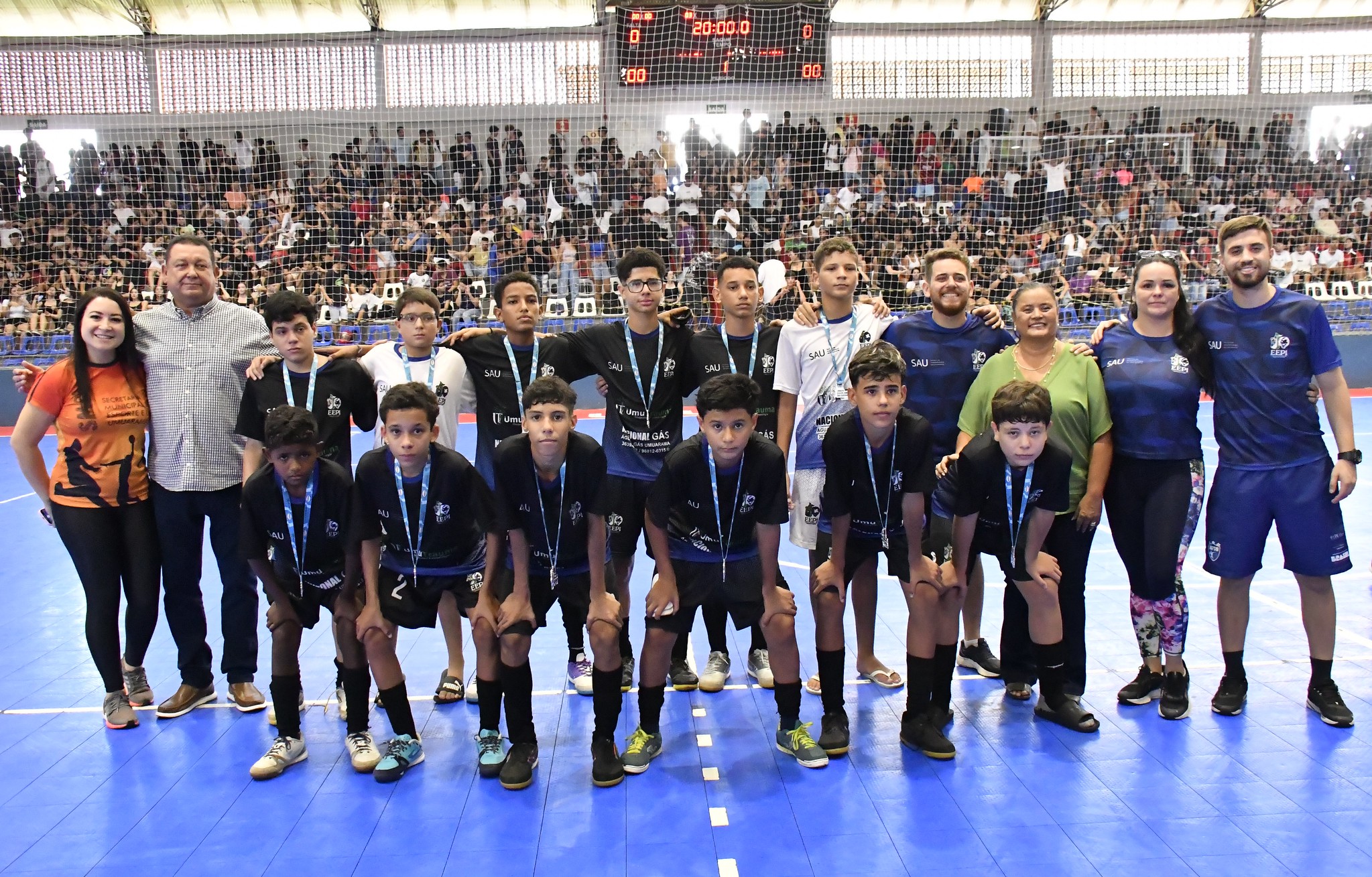 equipe campeã de futsal recebe medalhas no ginásio de esporte lotado