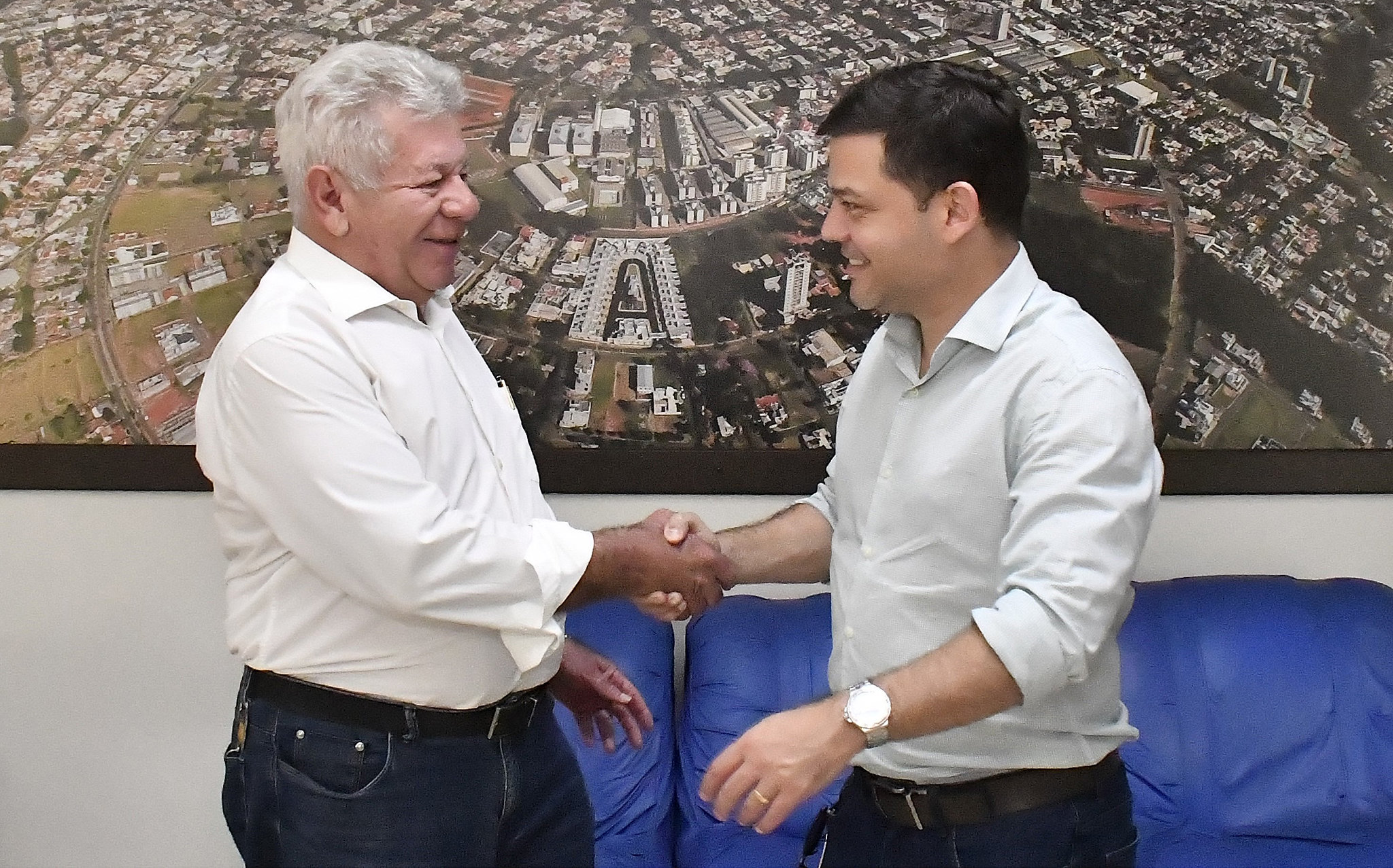 prefeito cumprimenta o deputado com foto da cidade ao fundo