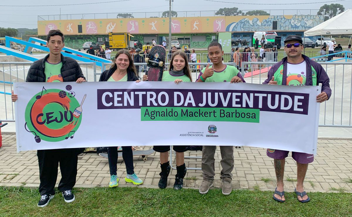 atletas e técnico com faixa do centro da juventude na frente do local da competição