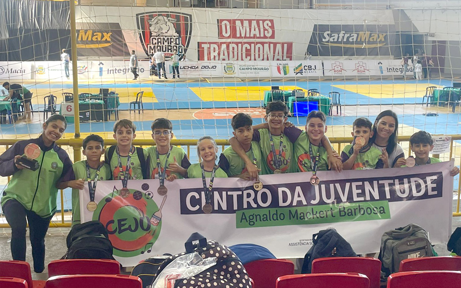 equipe de judô do centro da juventude, com vários meninos e meninas comemorando as medalhas