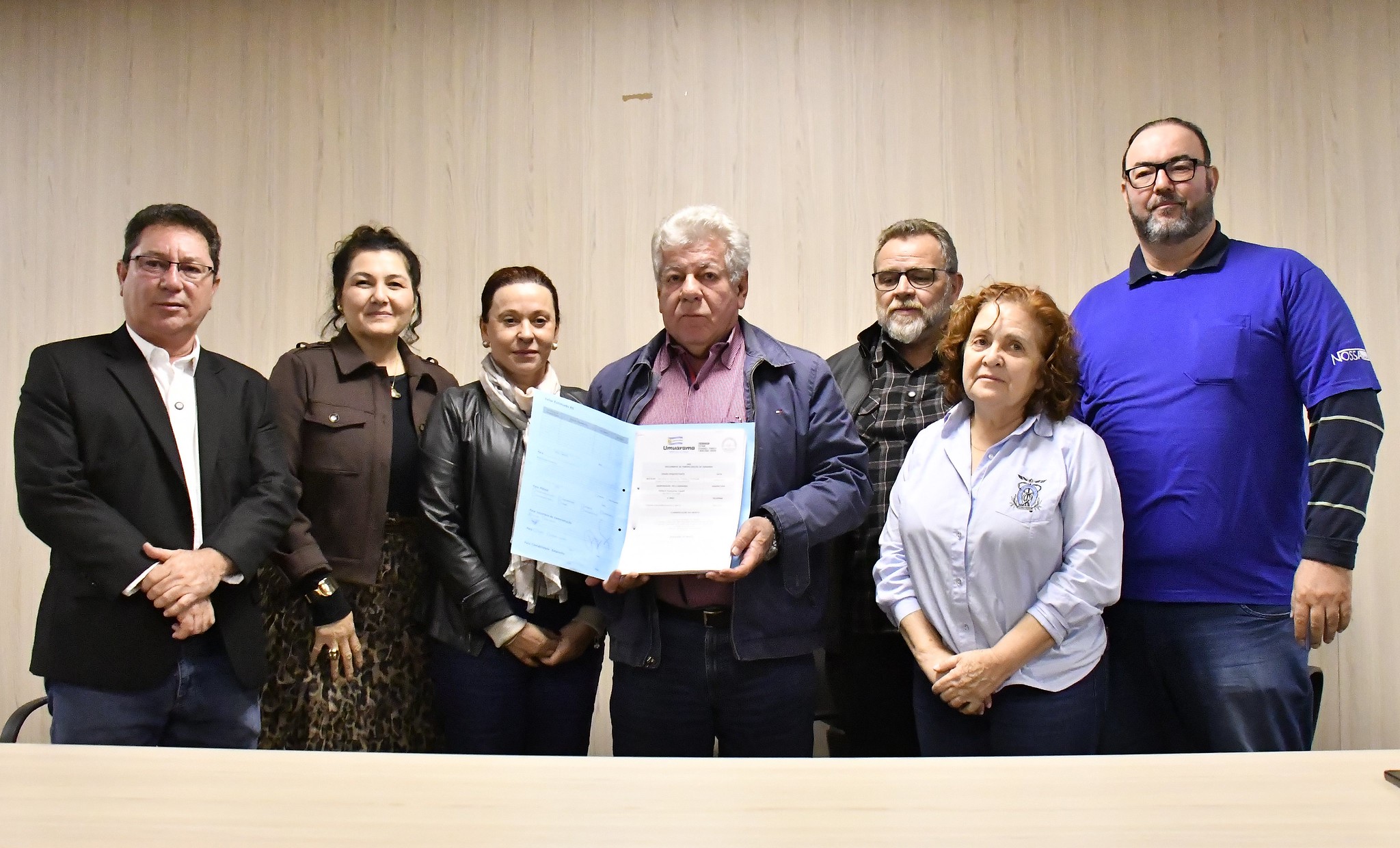 prefeito exibe na foto o edital de licitação para o estacionamento rotativo, ao lado de autoridades e políticos