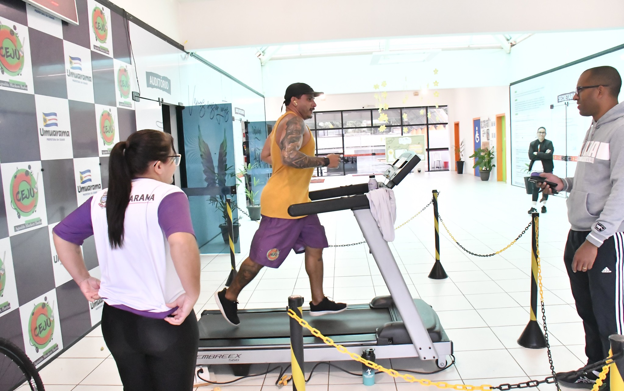 imagem de funcionário do centro da juventude correndo na esteira, sob o olhar dos colegas