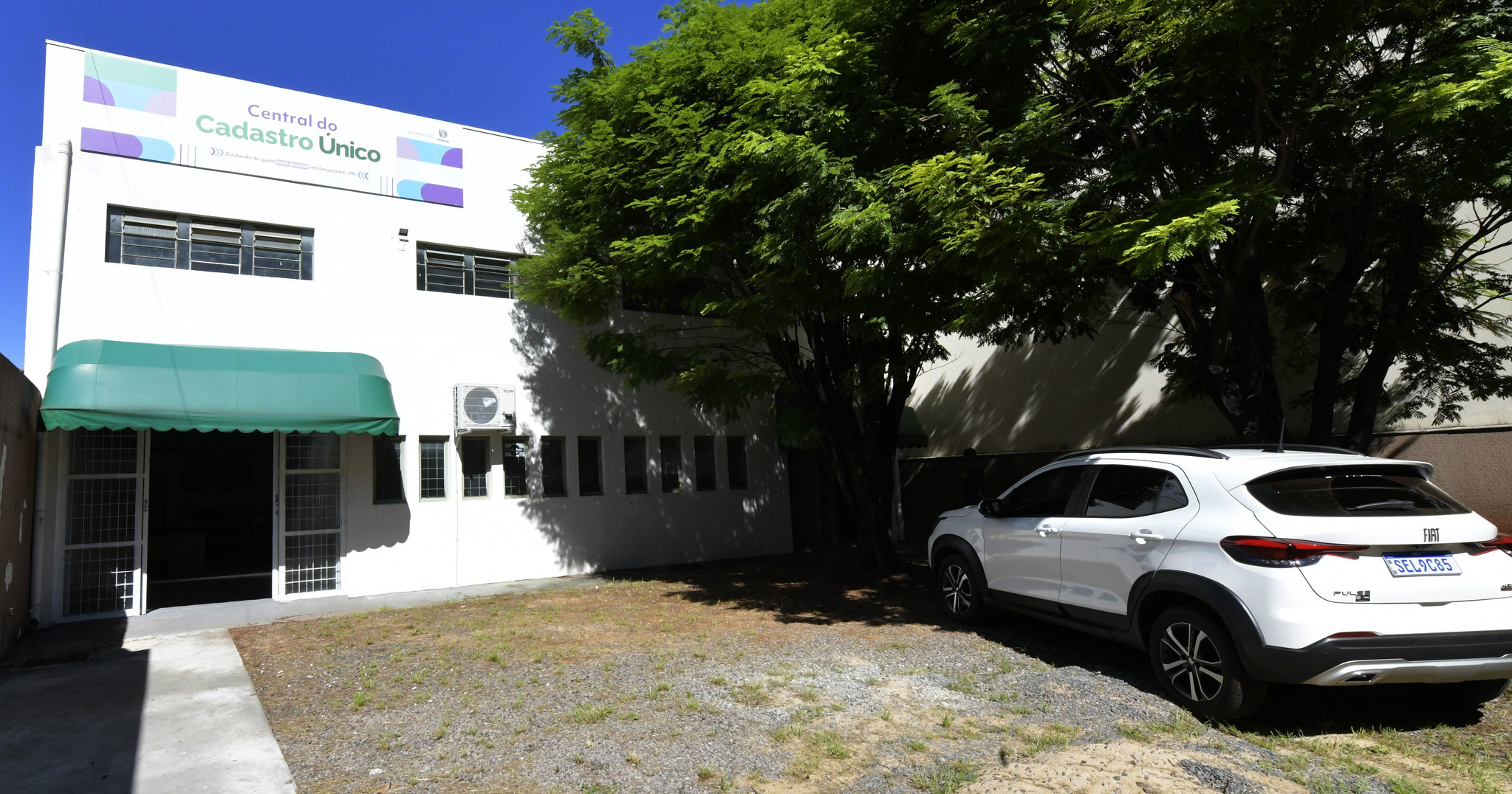 foto da fachada da central do cadastro unico, com carro estacionado ao lado