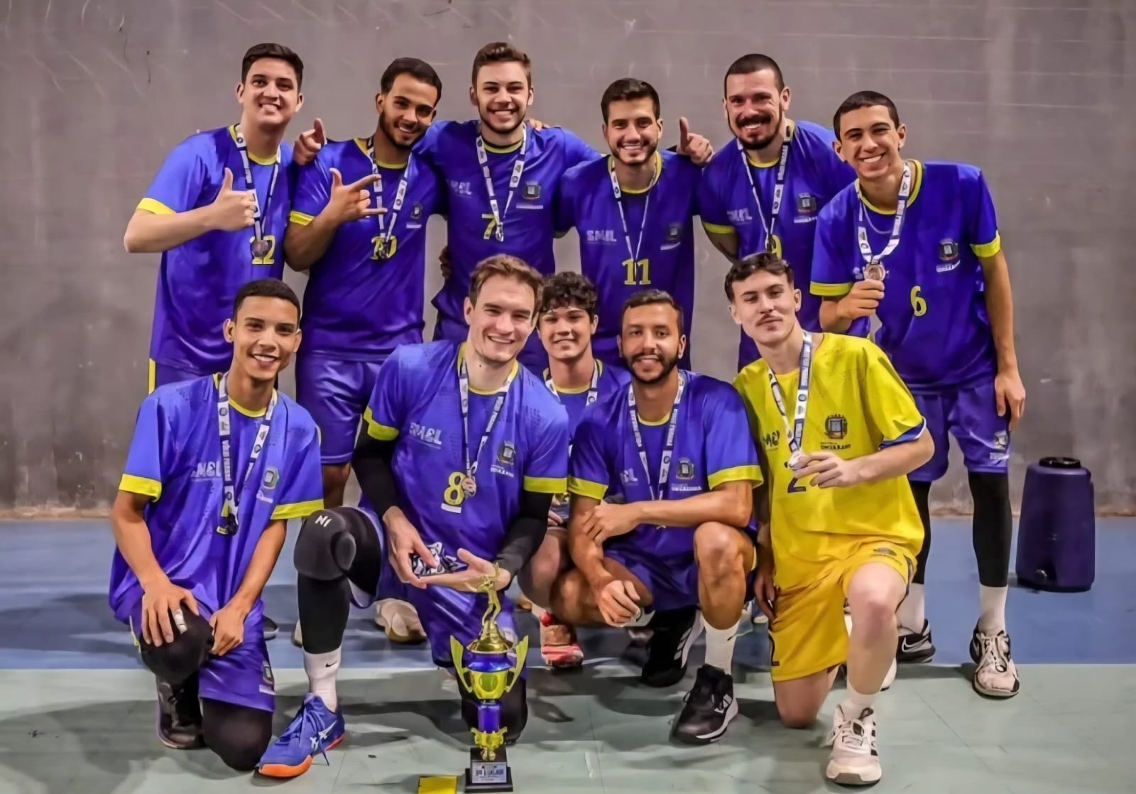 equipe de vôlei masculino posa para foto com medalhas conquistadas na competição