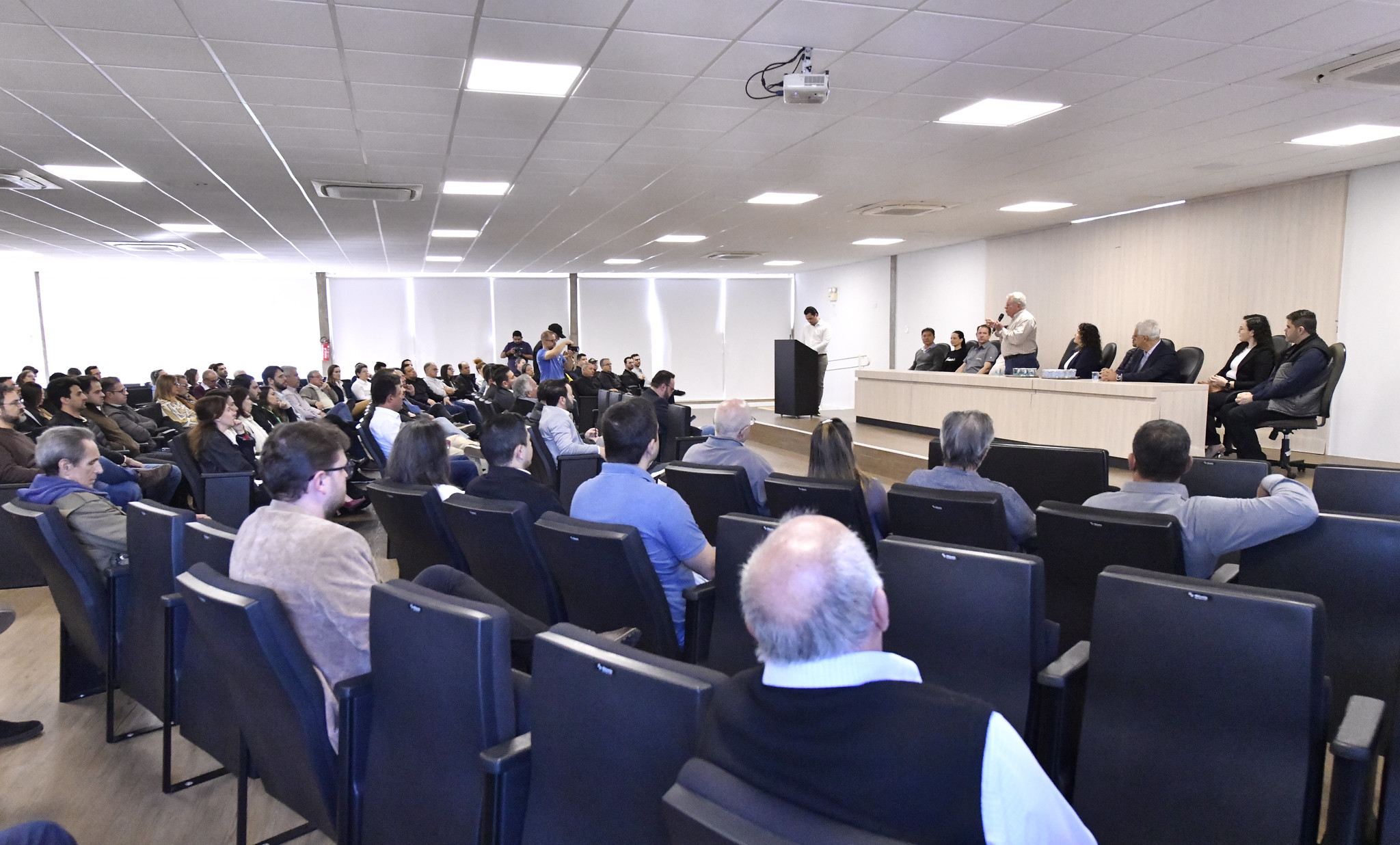 Imagem do anfiteatro da prefeitura, com participantes da reunião e a mesa diretora em destaque