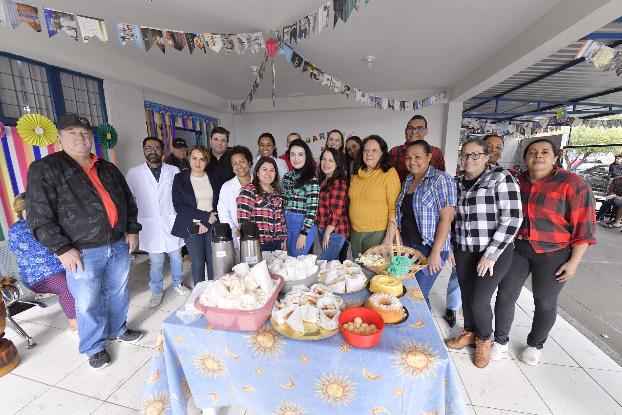 Equipes da UBS e da secretaria de saúde posam para foto diante da mesa de quitutes