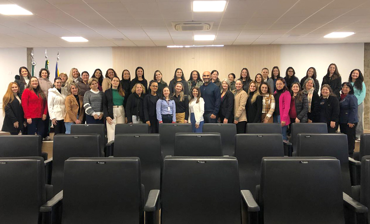 artigos musicais e culturais em primeiro plano e professores participantes do curso, no anfiteatro da prefeitura