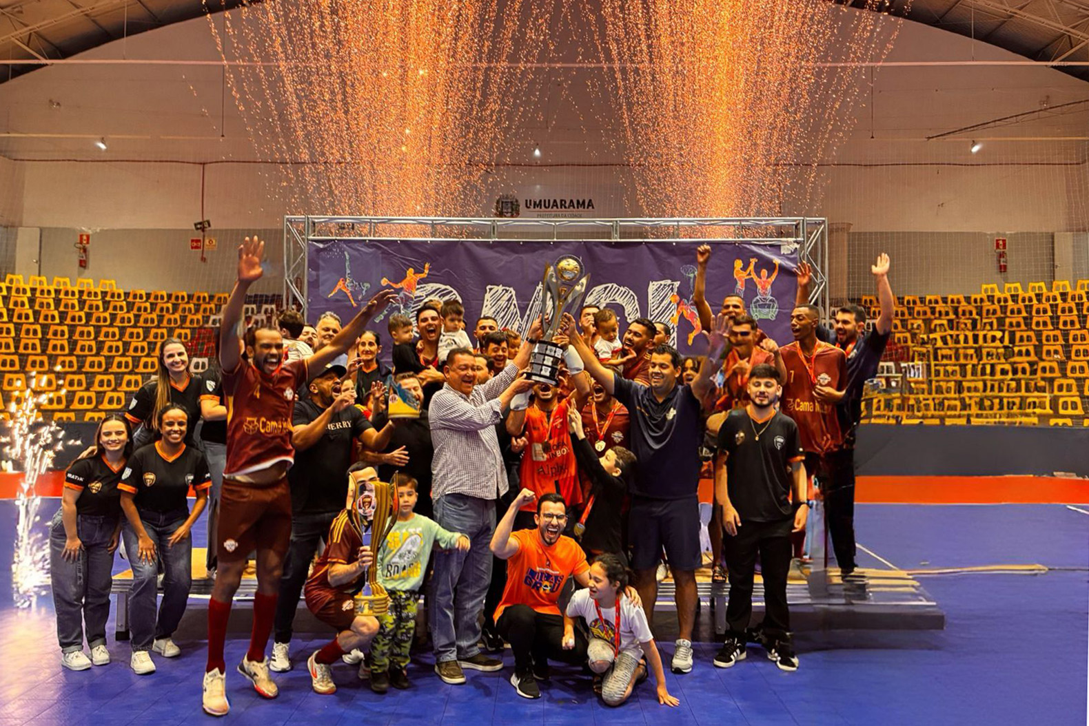 atletas da equipe vencedora comemoram o título com o troféu e festa na quadra de esportes