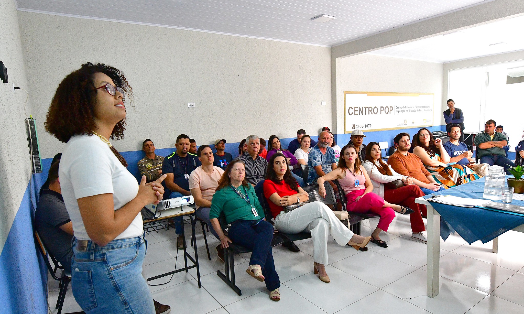 pessoas sentadas em sala de reuniões do centro pop, assistindo palestra