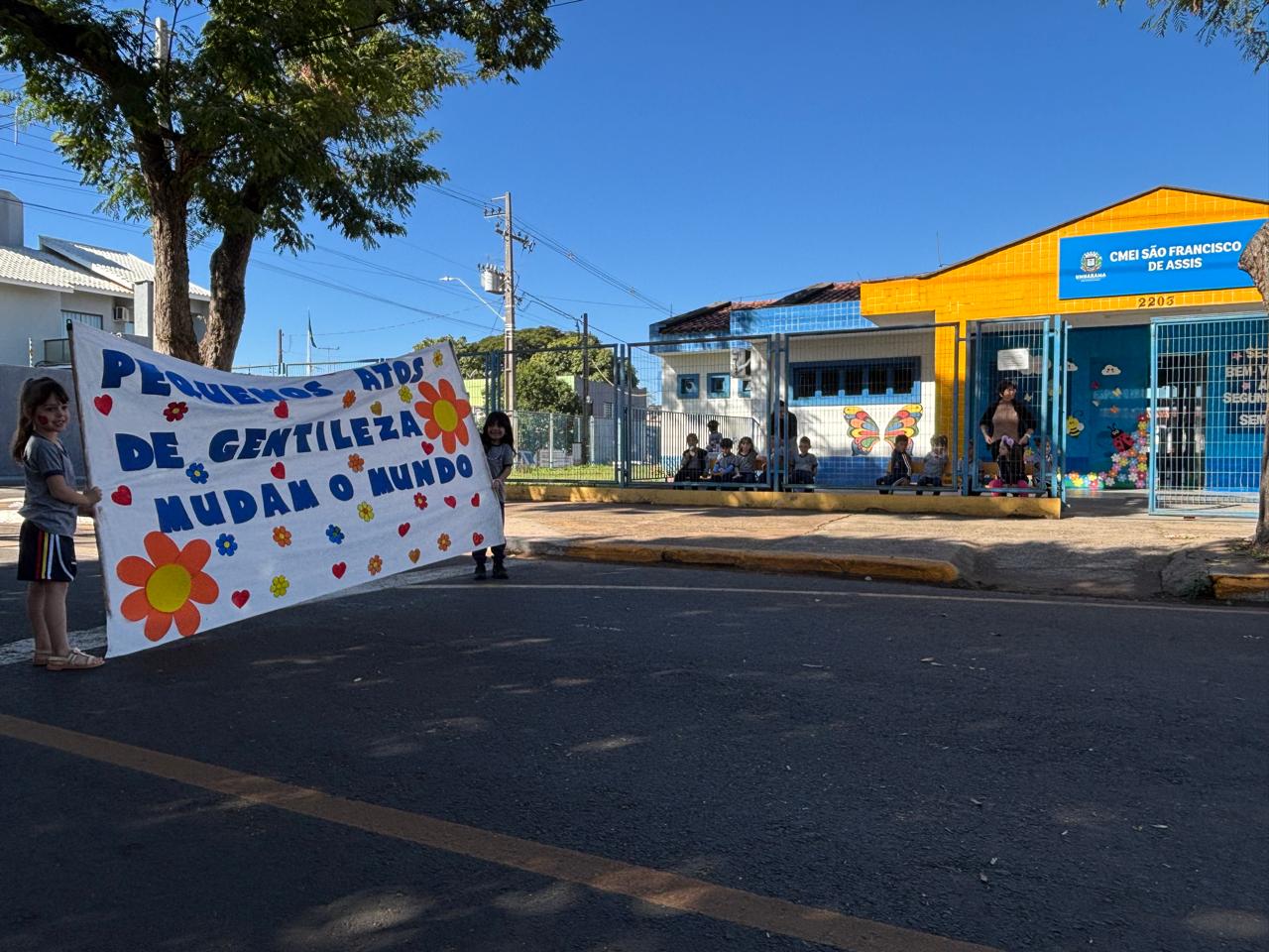 crianças seguram faixa do projeto na frente da escola infantil