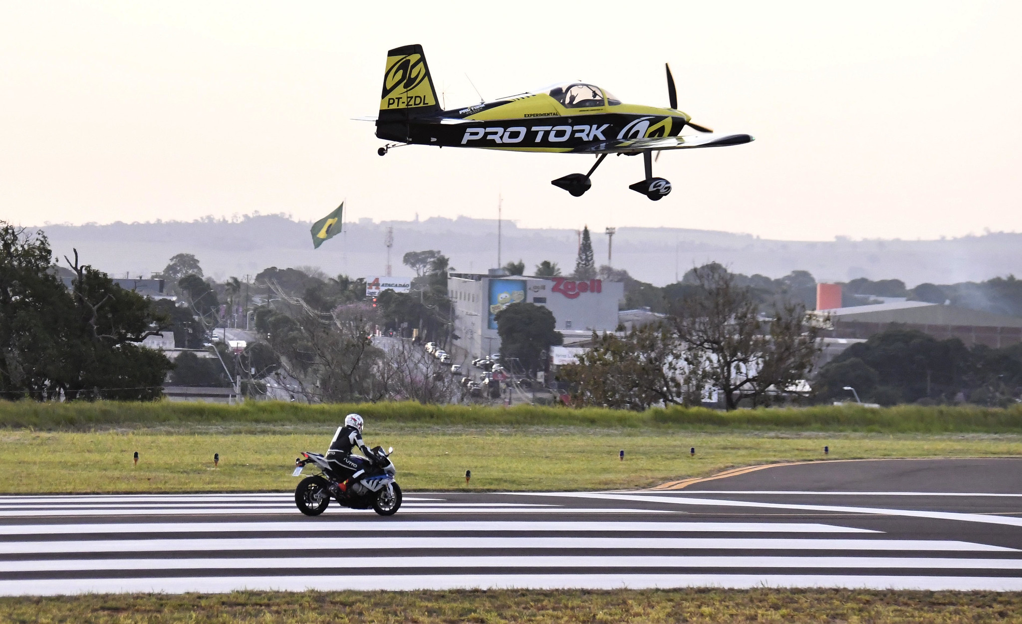 imagem de avião sobrevoando moto na pista do aeroporto
