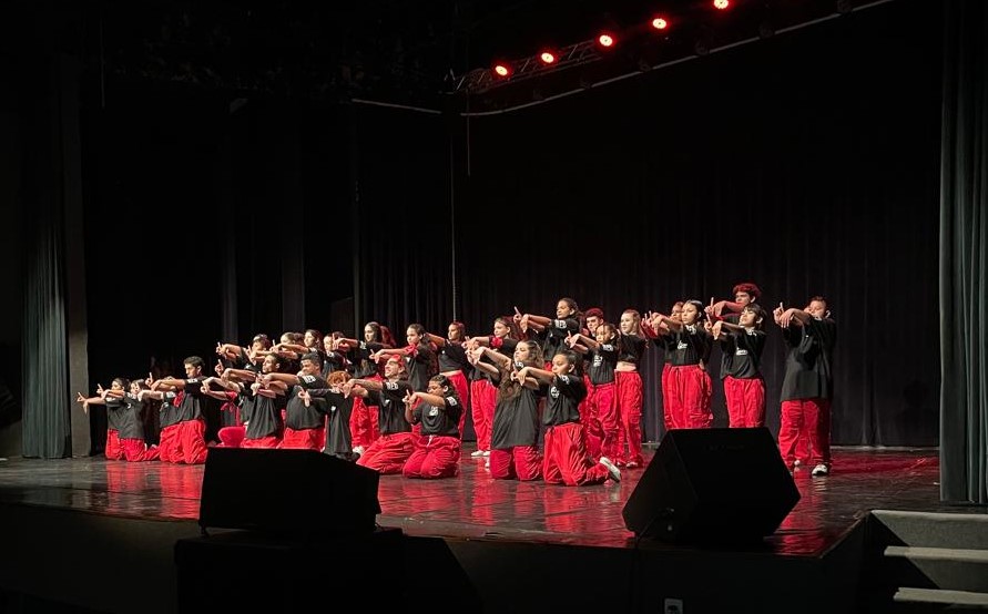 apresentação com grande grupo de dança no palco do teatro