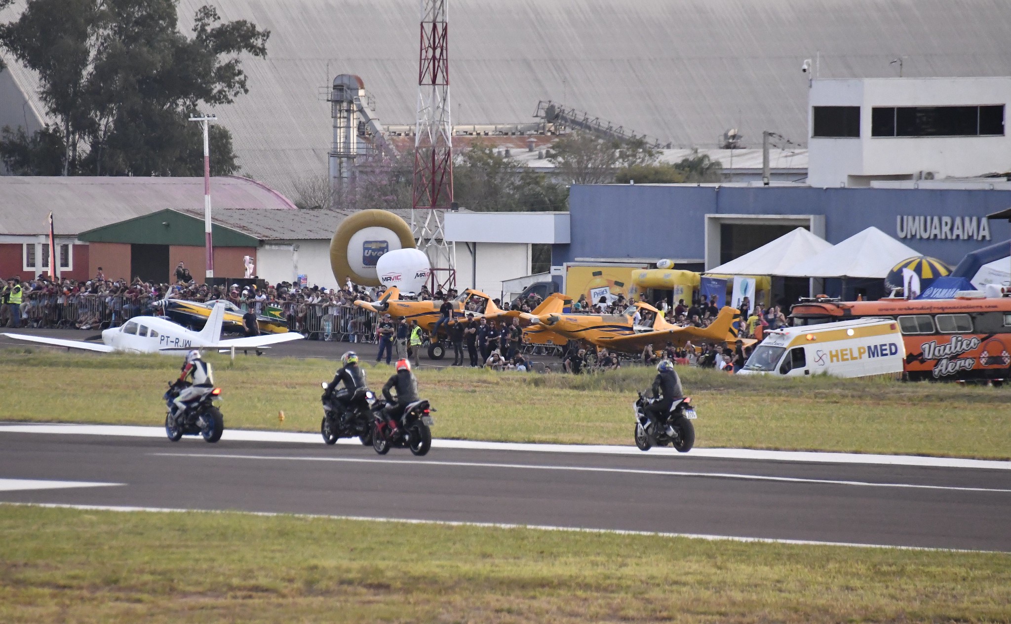 imagem do aeroporto com várias aeronaves, motos e público