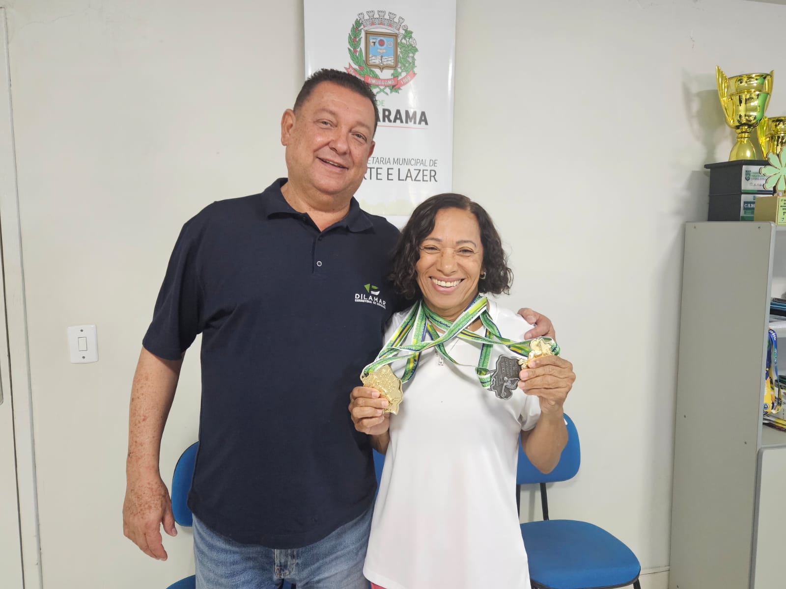 atleta exibe medalhas ao lado do secretário de esportes de umuarama
