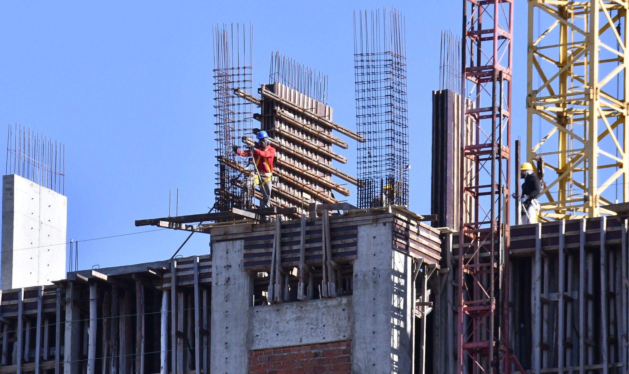 trabalhador da construção civil fixando armação de ferro em coluna de concreto