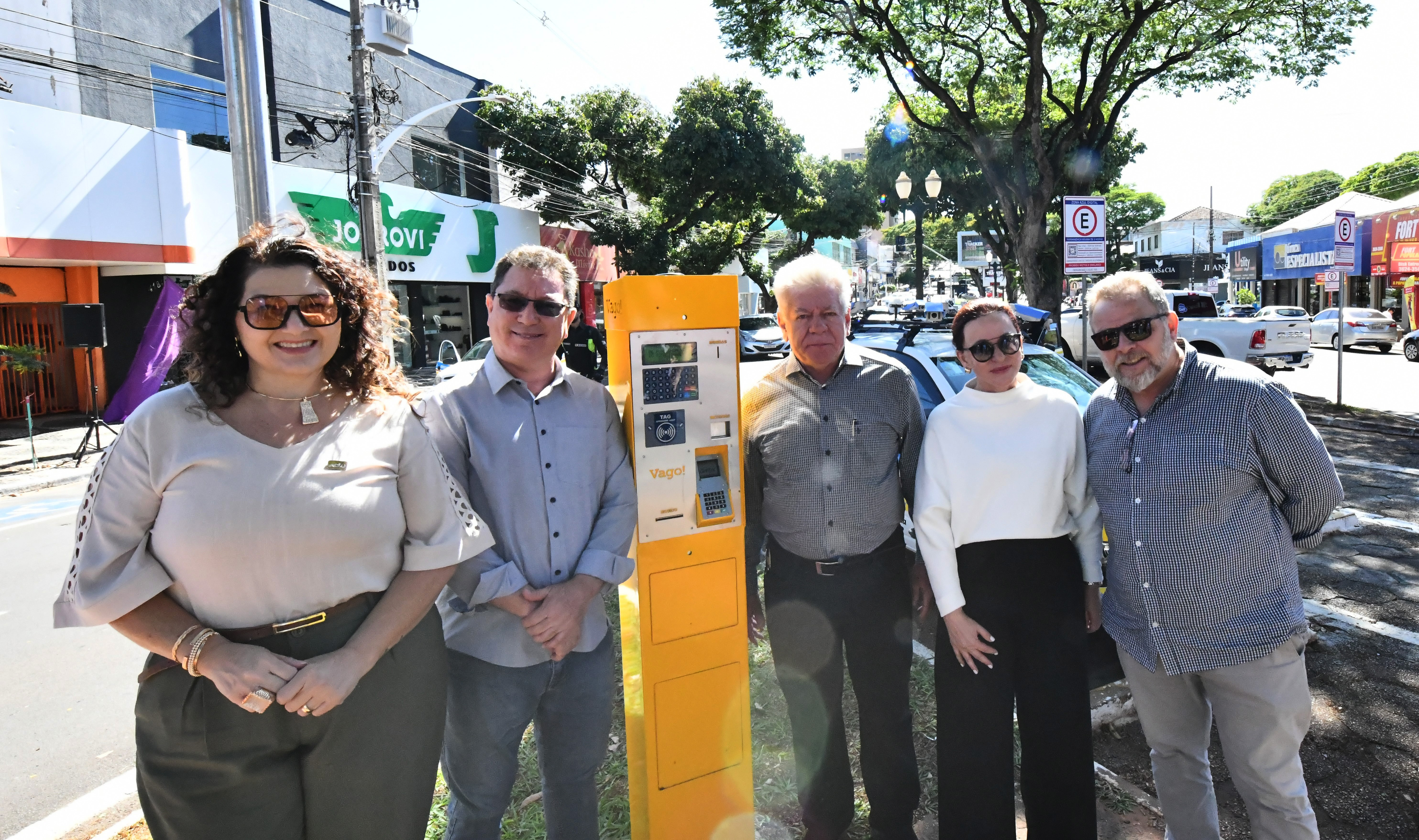 prefeito e autoridades ao lado de um parquímetro amarelo, no canteiro central da avenida