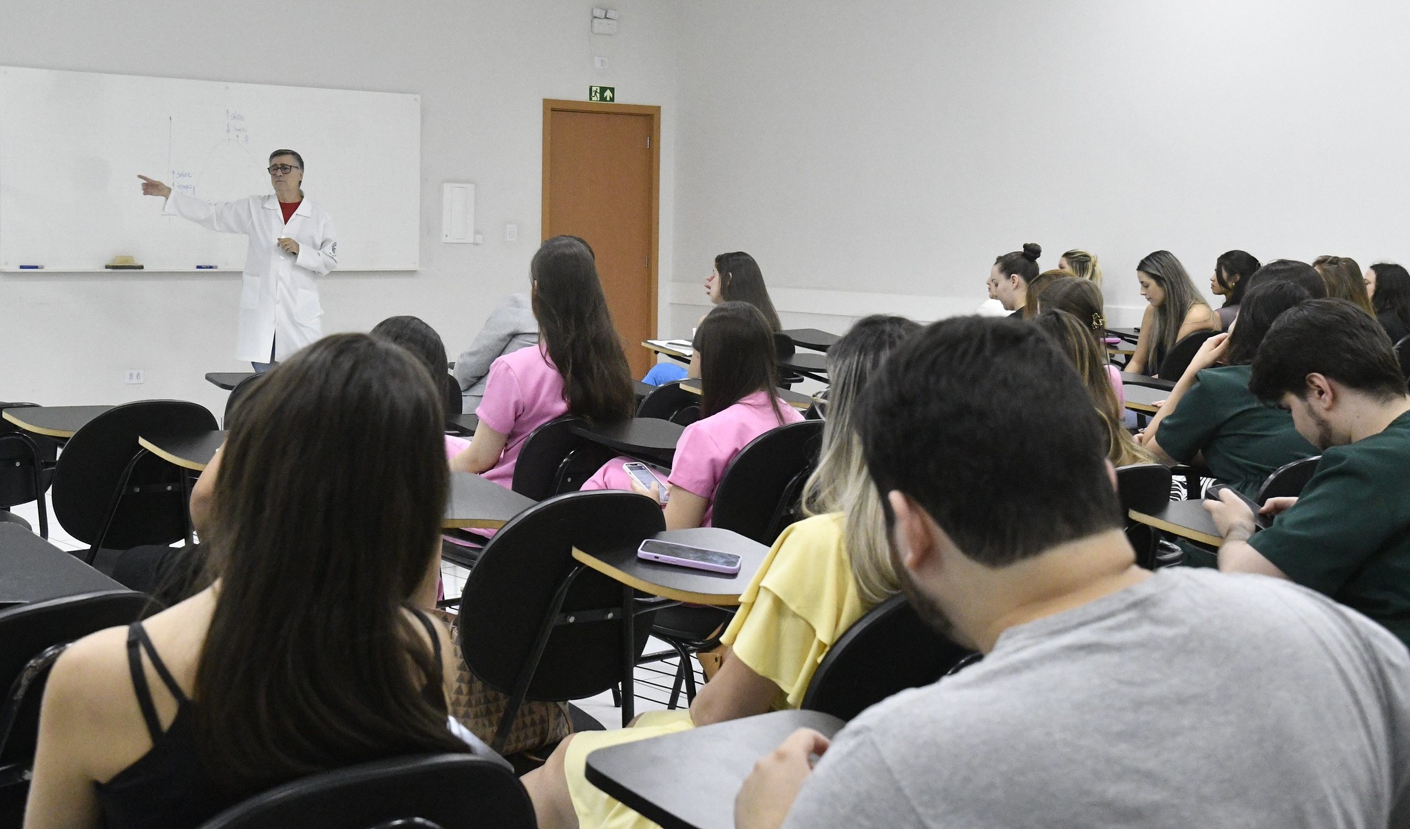 médico fala aos alunos à frente do quadro na sala de aula