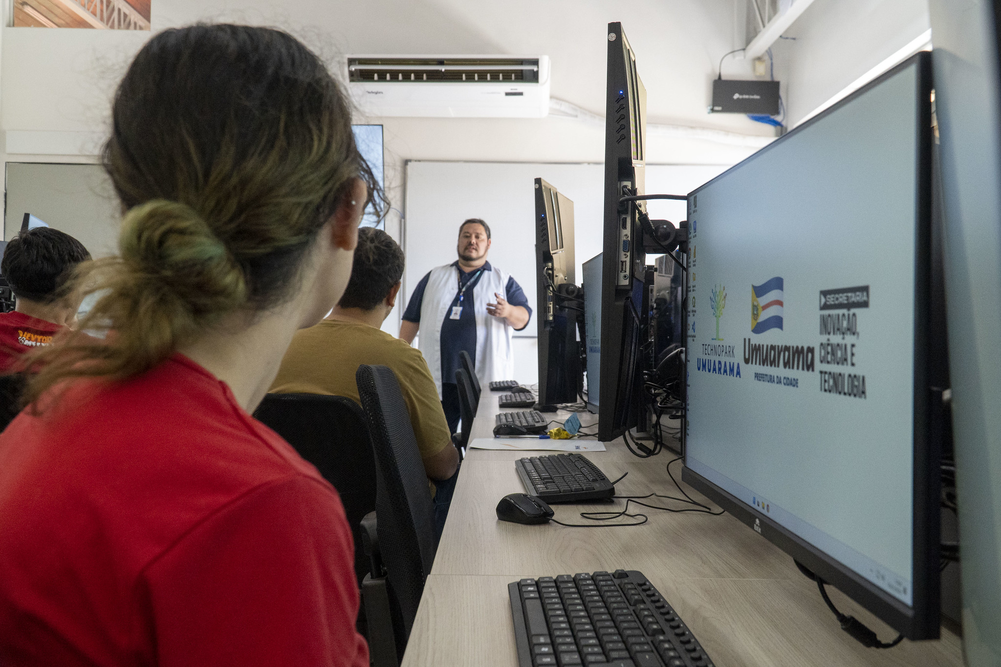 professor fala aos alunos do curso de computação, diante de computadores
