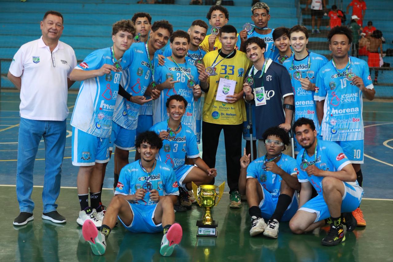 equipe de handebol masculino exibe o troféu conquistado pelo terceiro lugar