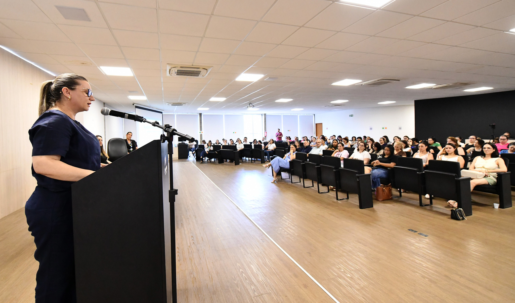 secretária da educação fala ao público no auditório da Prefeitura