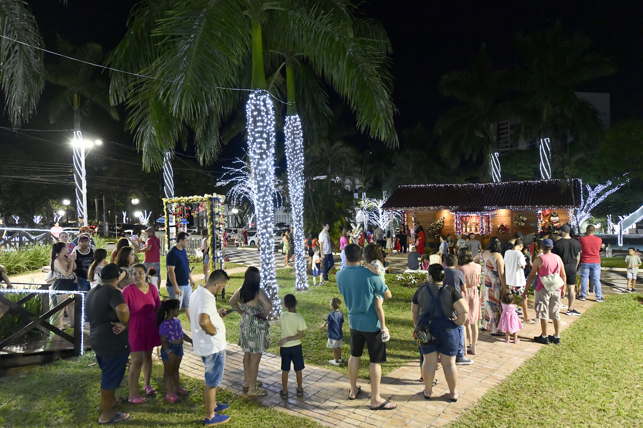 foto da casinha do papel noel decorada com muitas luzes e fila de visitantes