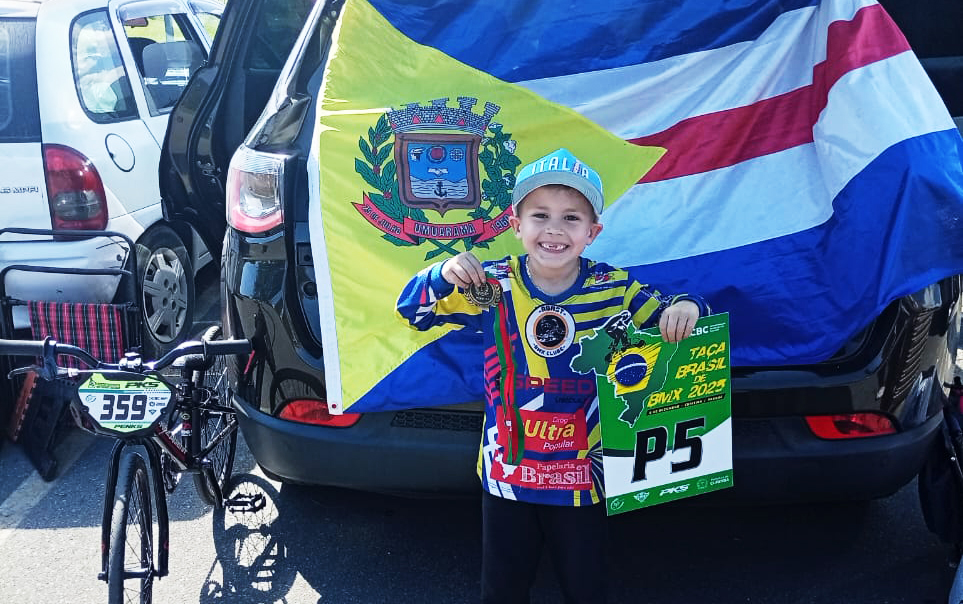 o pequeno Lorenzo exibe a medalha e o troféu conquistados na competição