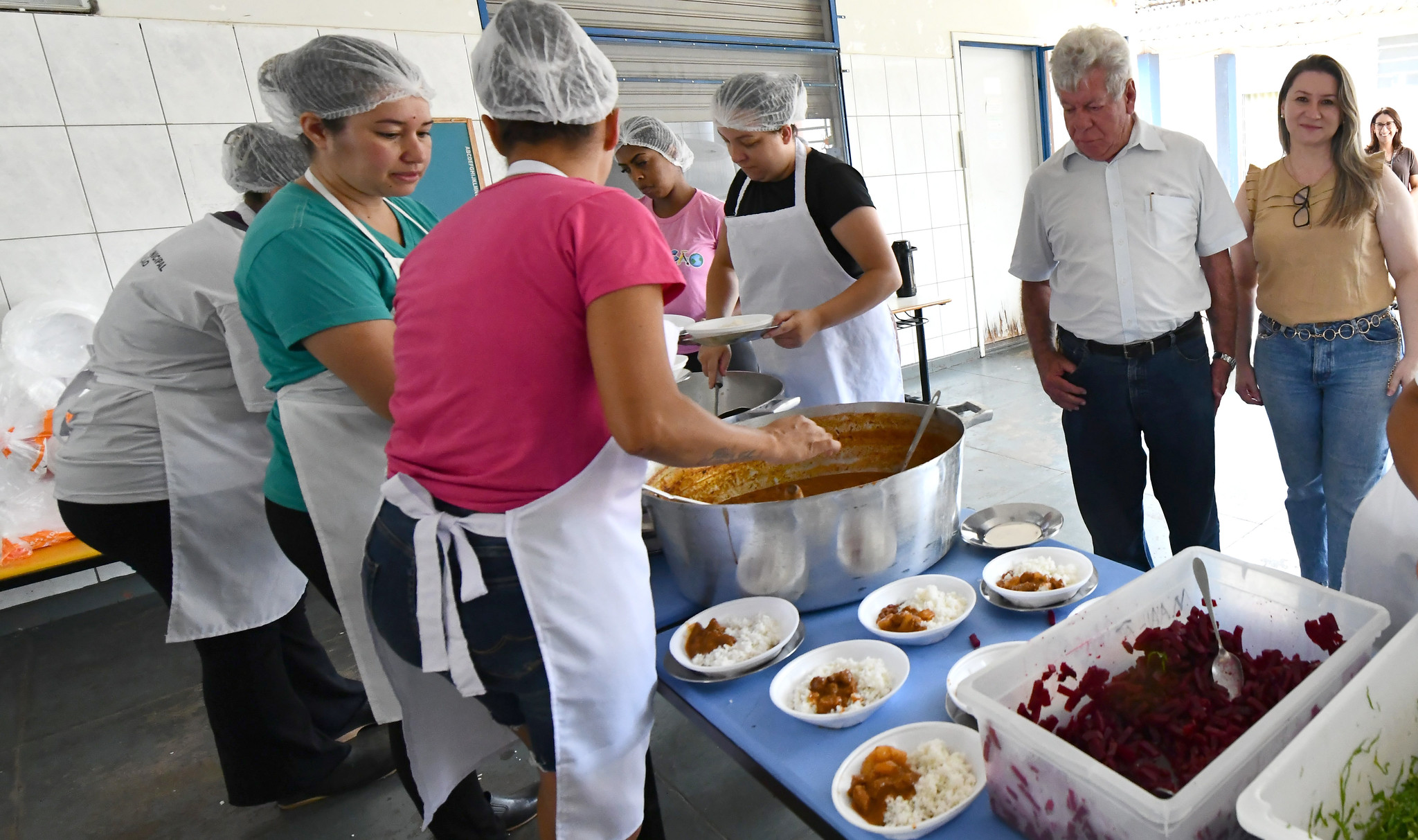 prefeito observa o trabalho das merendeiras, preparando marmitas para os alunos em férias