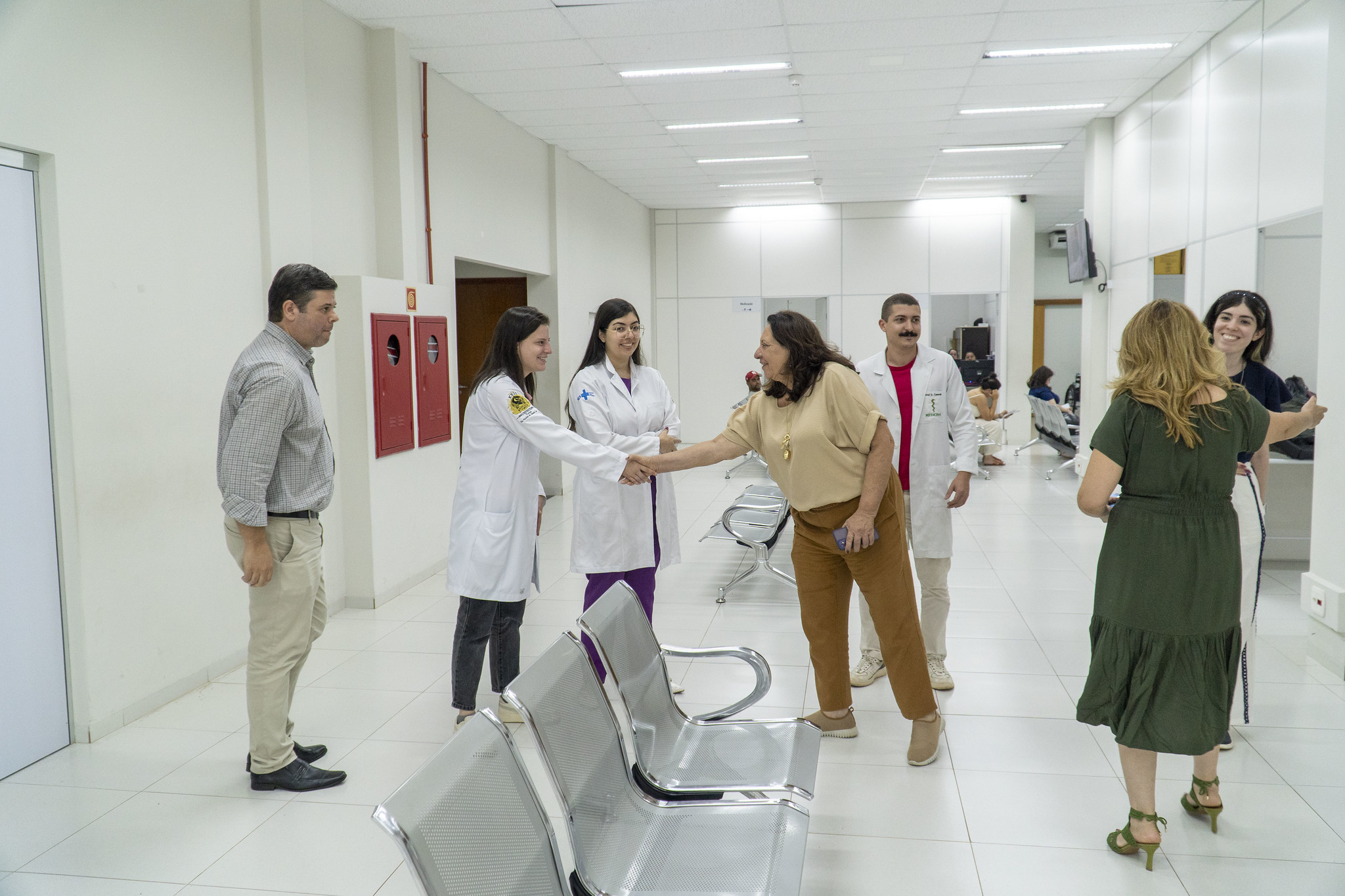 secretária cumprimenta profissionais durante visita à unidade de saúde