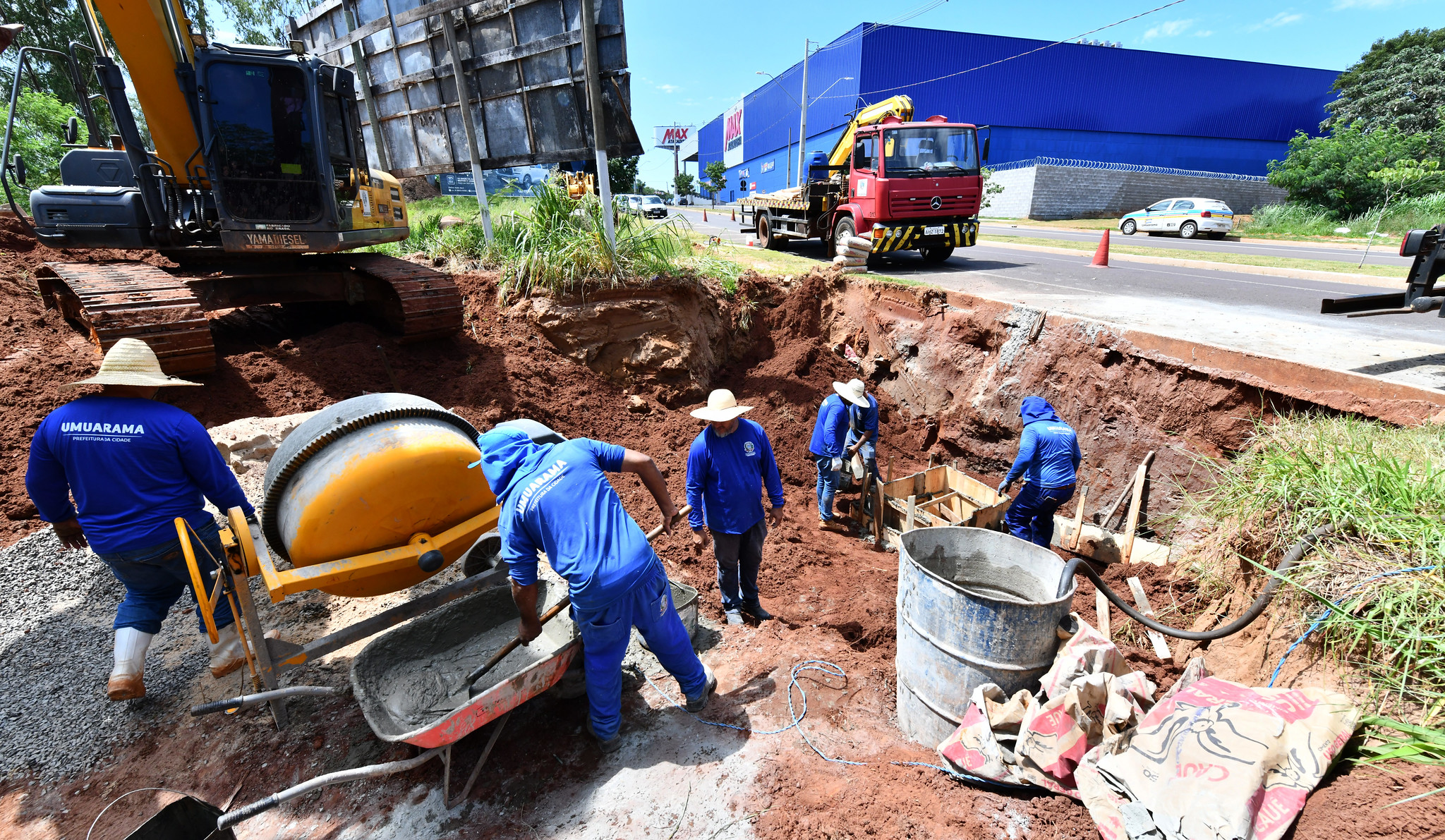 trabalhadores realizam serviço com concreto ao lado de avenida
