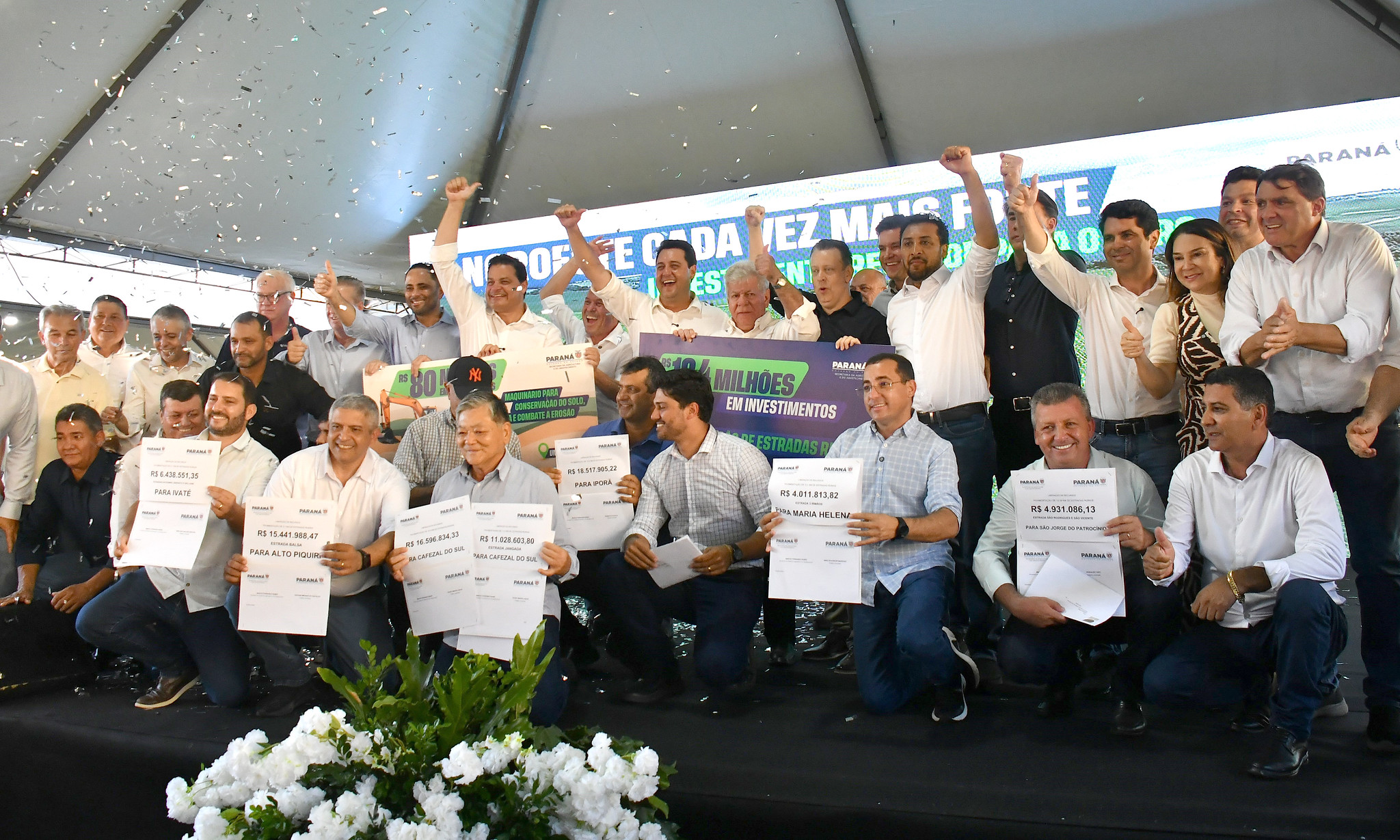 imagem de políticos comemorando a liberação de recursos sobre o palco