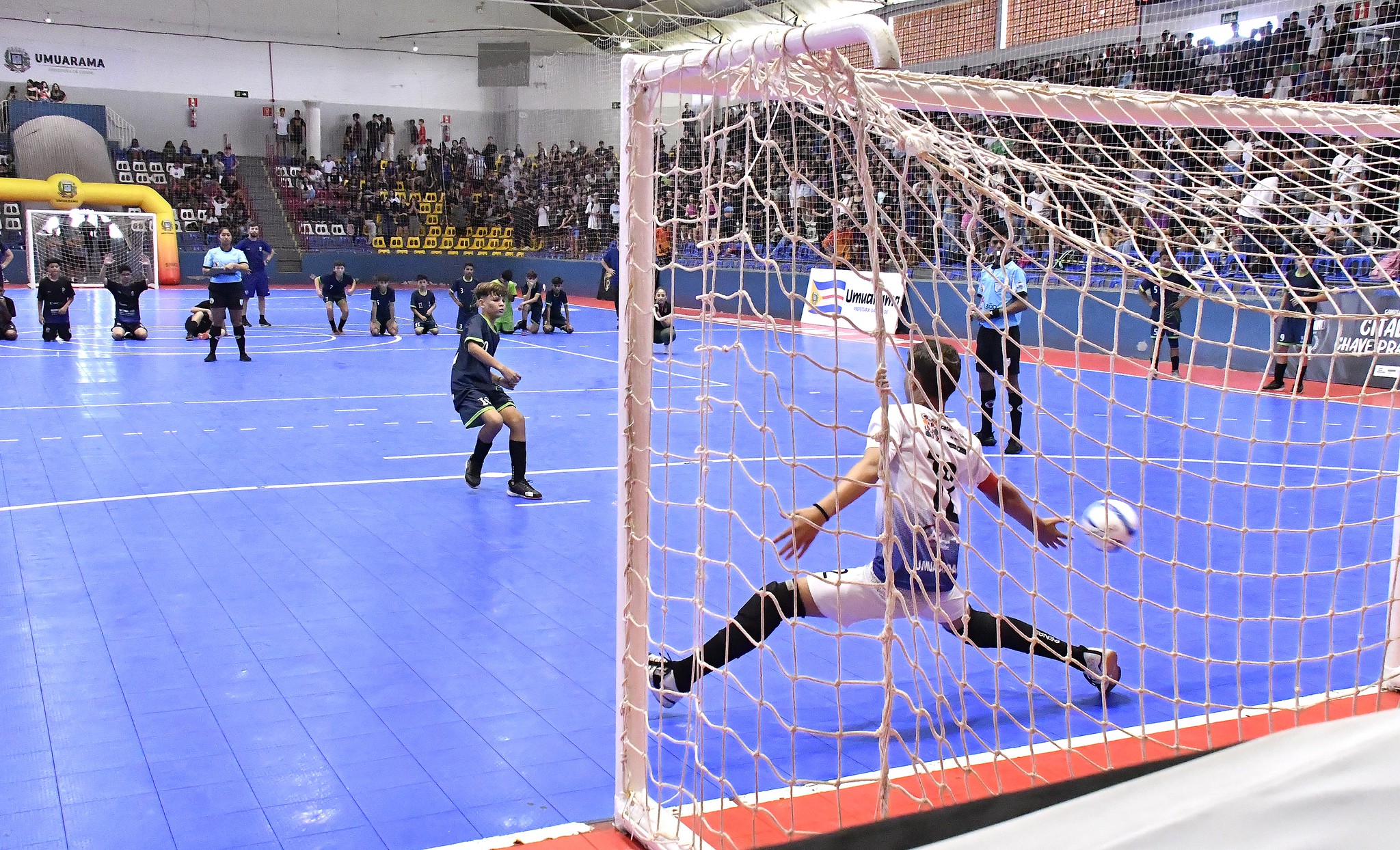 jogo de futsal com atletas jovens em quadra esportiva