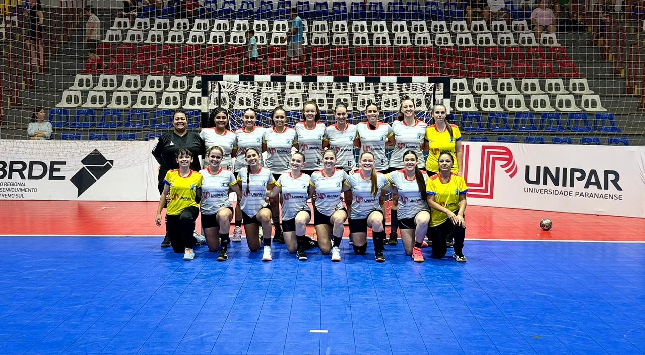 Foto da equipe feminina de handebol em uma quadra de esportes