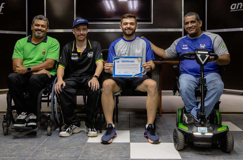 professor exibe certificado ao lado de técnicos cadeirantes