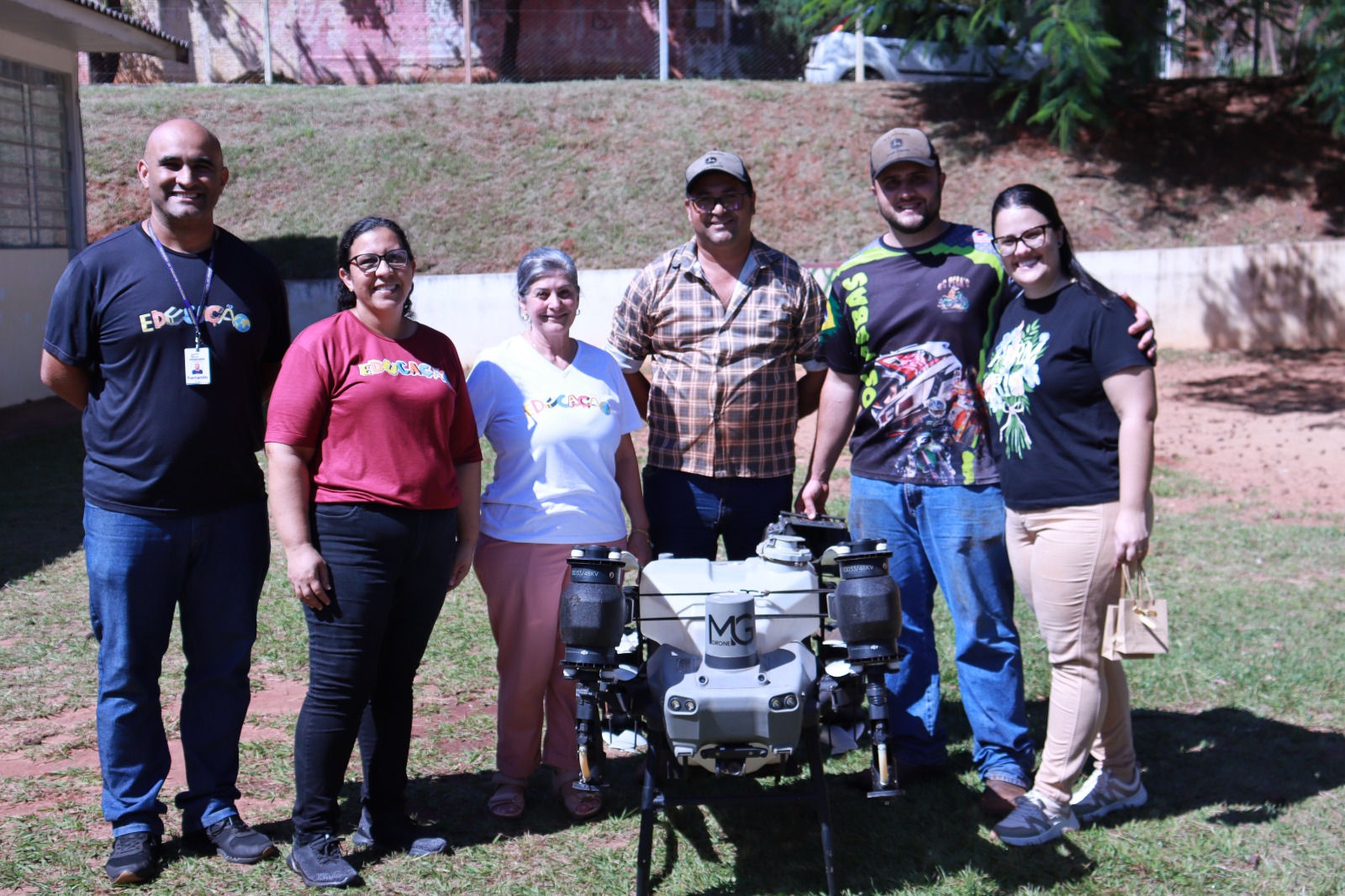 equipe da escola, professores e produtor rural com o drone agrícola usado na apresentação
